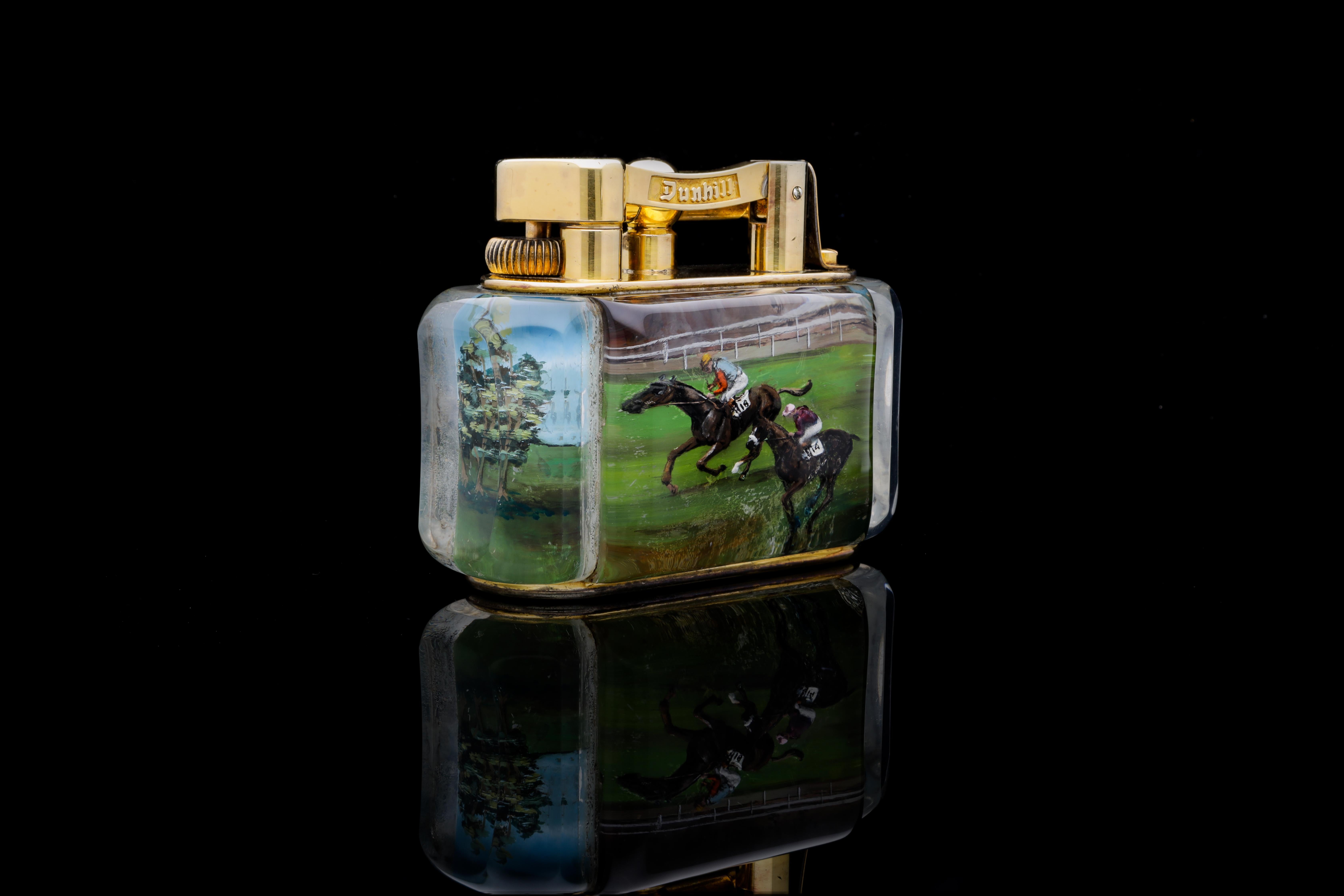 An exceptional and rare Special Commission Dunhill Sporting Horse Racing Half-Giant 'aquarium' Table Lighter in Gold Plate. 

The top with raisable arm stamped Dunhill and Reg. No 737418 on the reverse, above the lucite body carved with the