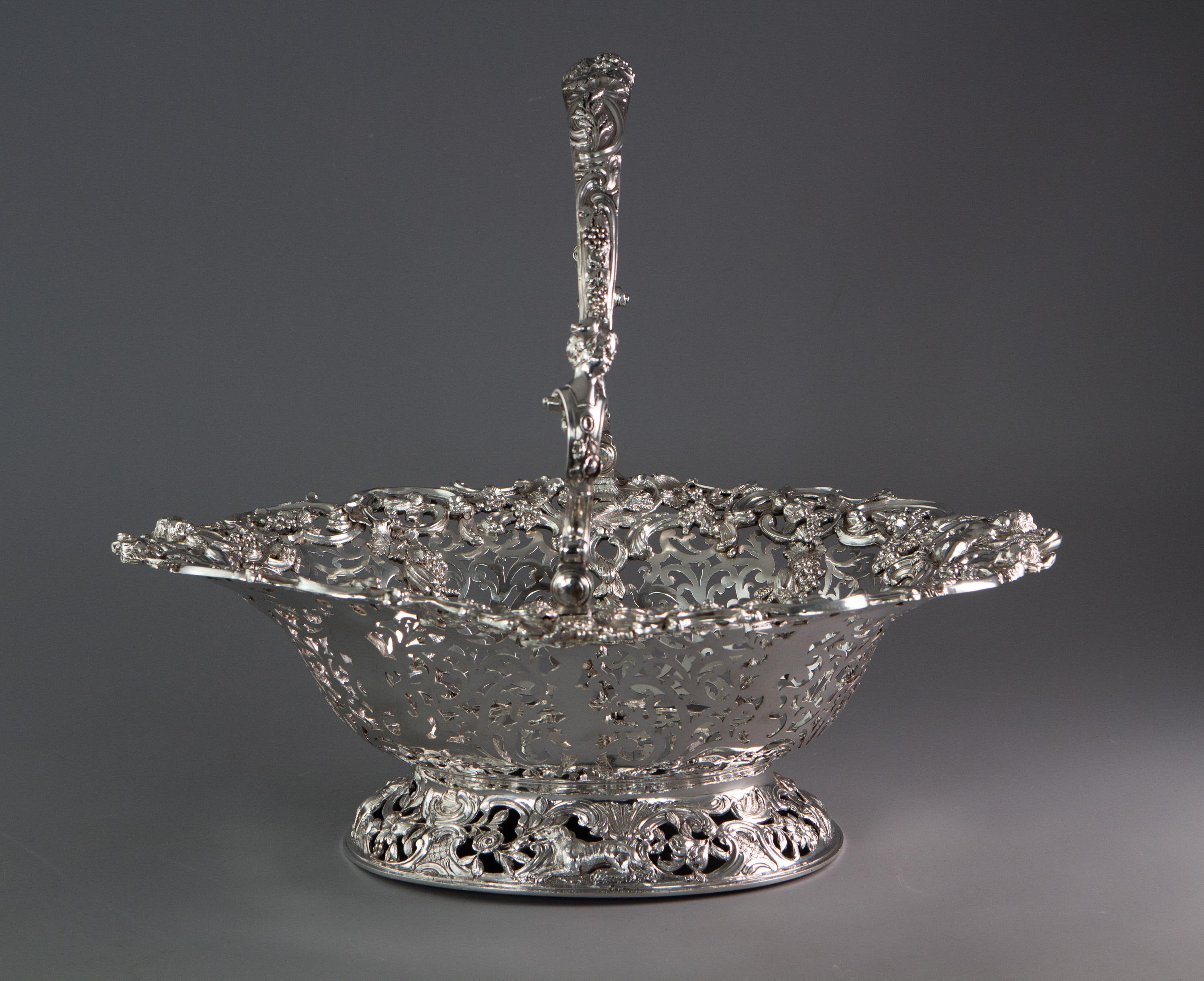 A very large George II silver swing handle harvest basket by William Tuite. Of pierced oval form, adorned with an immaculately cast rim decorated with scrolls, wheat sheaves and grapes surrounding four putti collecting the harvest. Each of the eight