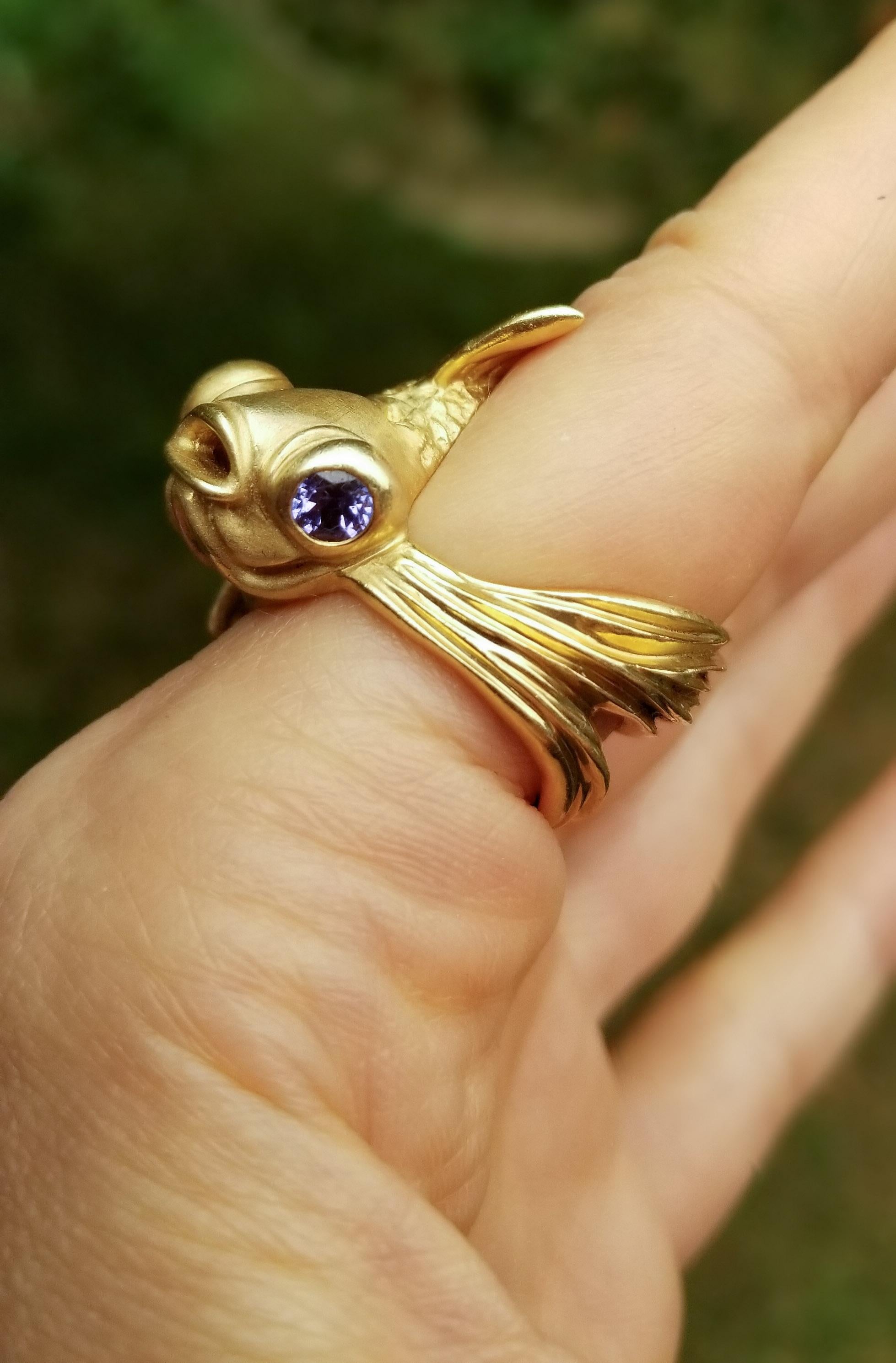 18ky gold, tanzanites, diamonds. One-of-a-kind.

A symbol of good luck, good fortune, and fortitude, this Goldfish swims by on the wearer's hand, his gold body glistening and his tanzanite eyes sparkling.
His sinuous body wraps gracefully around a