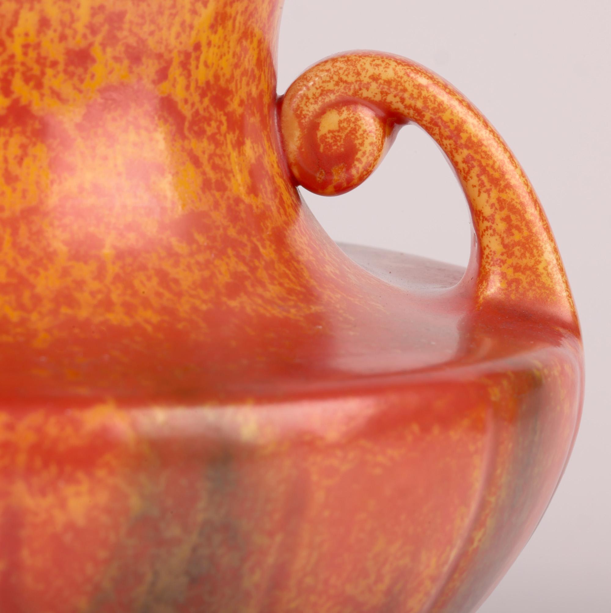 A stunning Art Deco Royal Lancastrian Pilkington twin handled art pottery vase of amphora shape decorated in vermilion orange glazes and dating from around 1920. The well-made earthenware vase stands on a narrow round unglazed foot with recessed