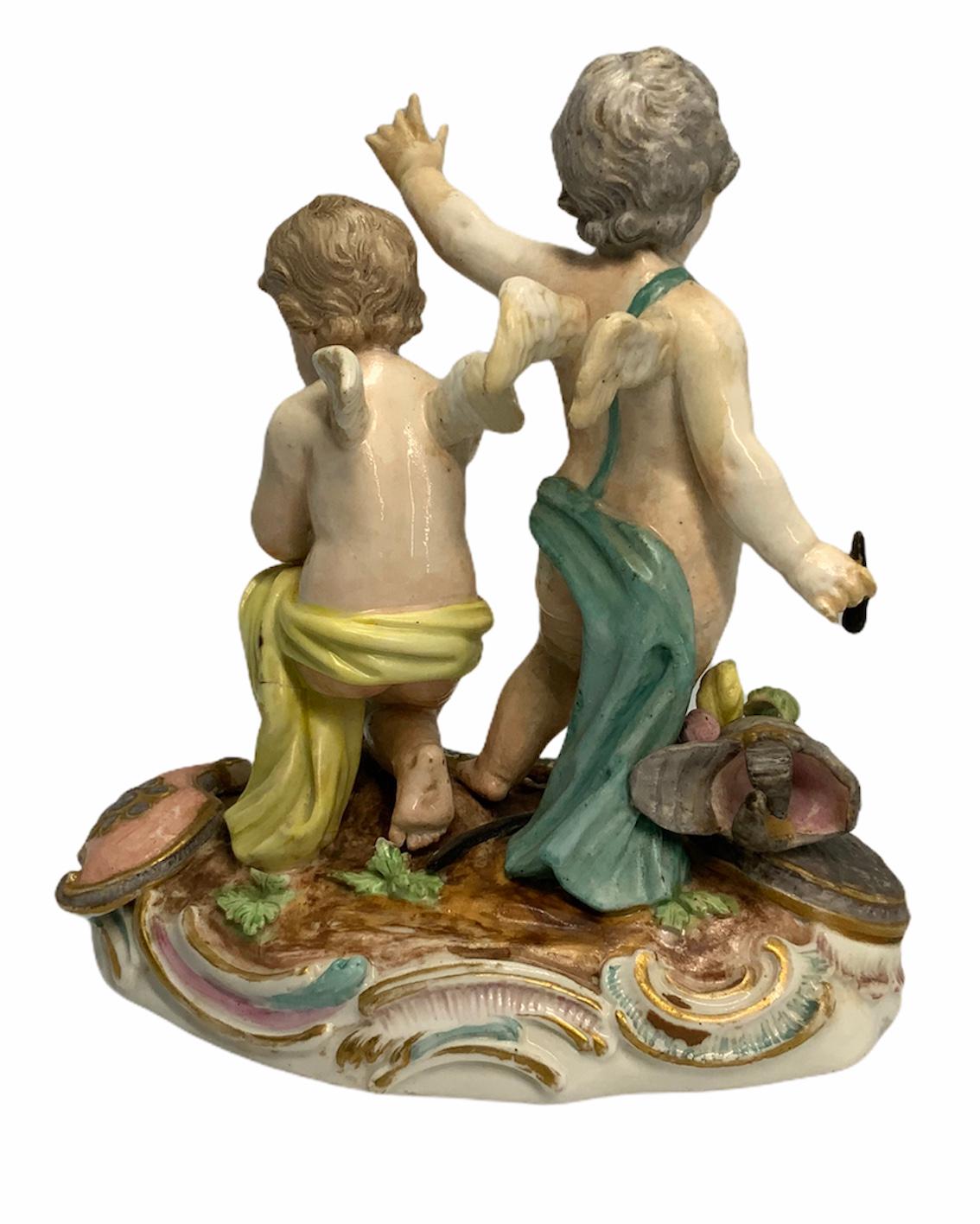This rare porcelain group sculpture depicts a pair of winged warriors cherub figurines. They are without their helmet, armor, and swords. One is in a victorious posture and the other one is thoughtful and down in one knee holding his helmet. The