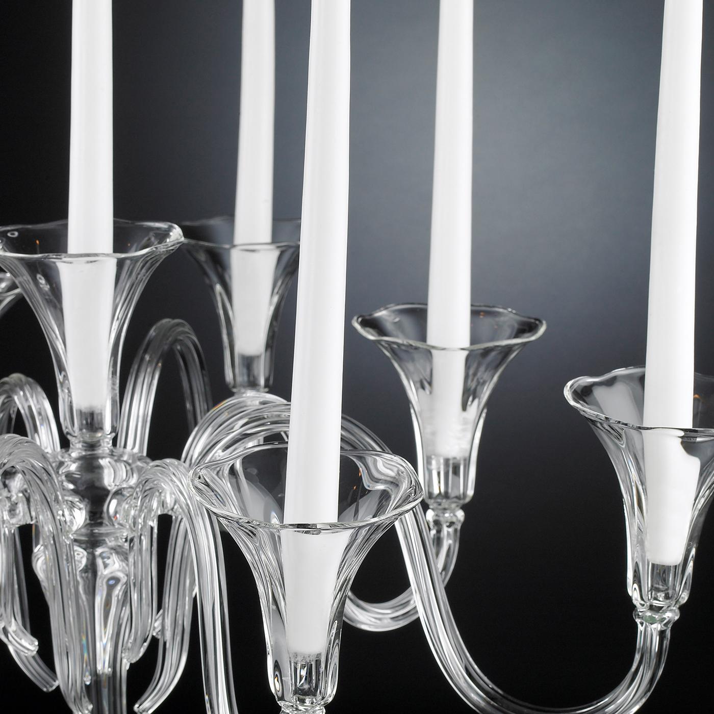 A striking objet d'art that will enliven any dining table with refined sophistication, this candle holder is composed of nine upward-curved arms mounted on a thin yet tall stem. This splendid piece is entirely crafted of transparent glass by master