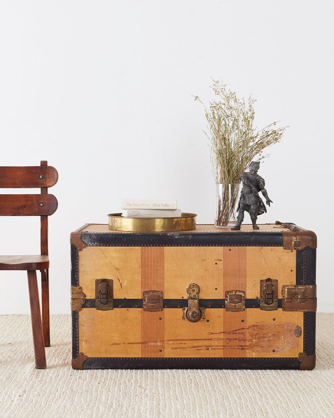 Vintage canvas standing wardrobe steamer trunk manufactured by Royal Robe. Features a colorful striped exterior with black fiber straps and brass nailheads accenting the borders. The metal has a vintage patina and the initials on top M. Mc. R. The