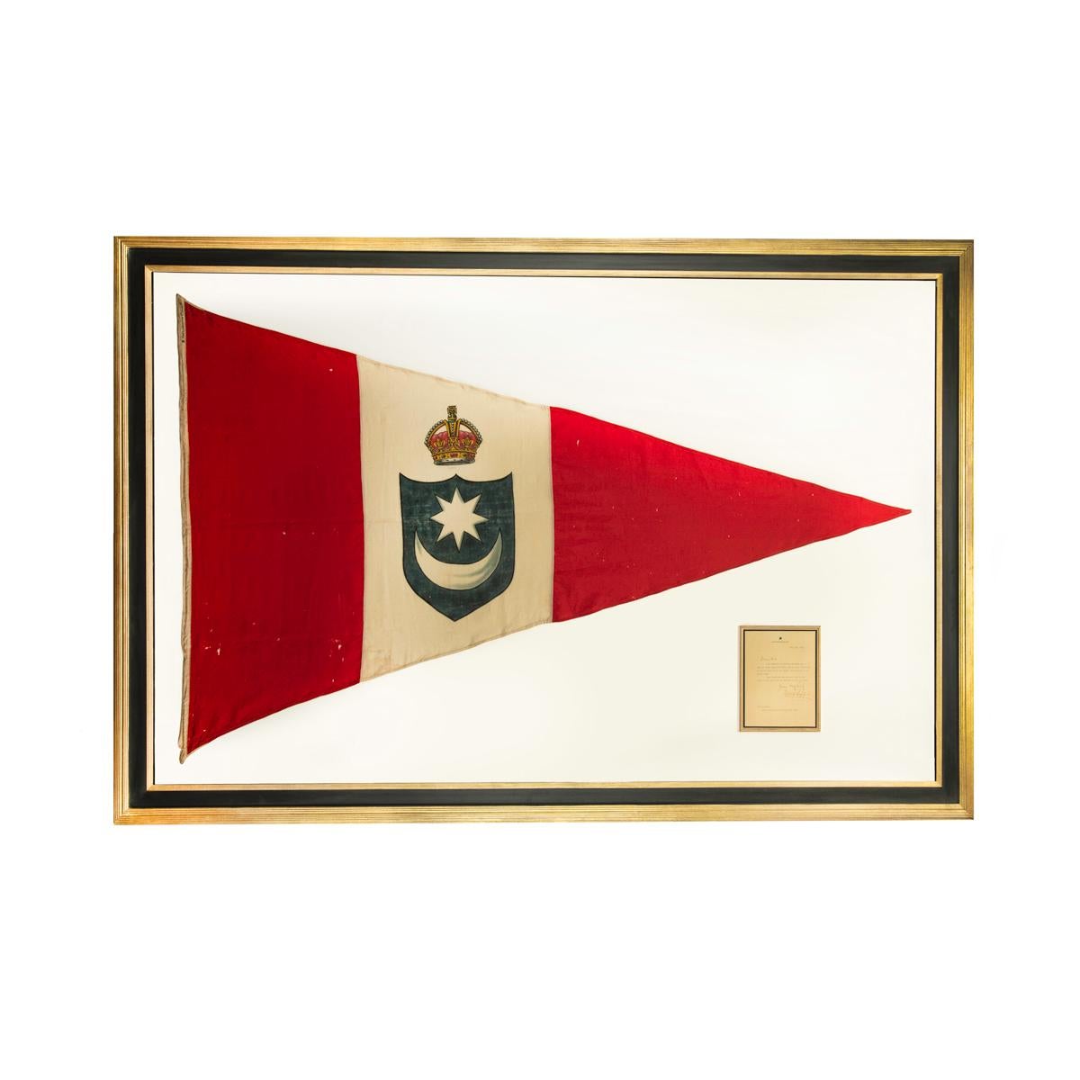 This large triangular racing burgee is made from pieced wool bunting with machine stitching with three vertical red, white and red stripes.  The white stripe showing a blue shield with a white star and crescent moon motif below a royal crown.  The