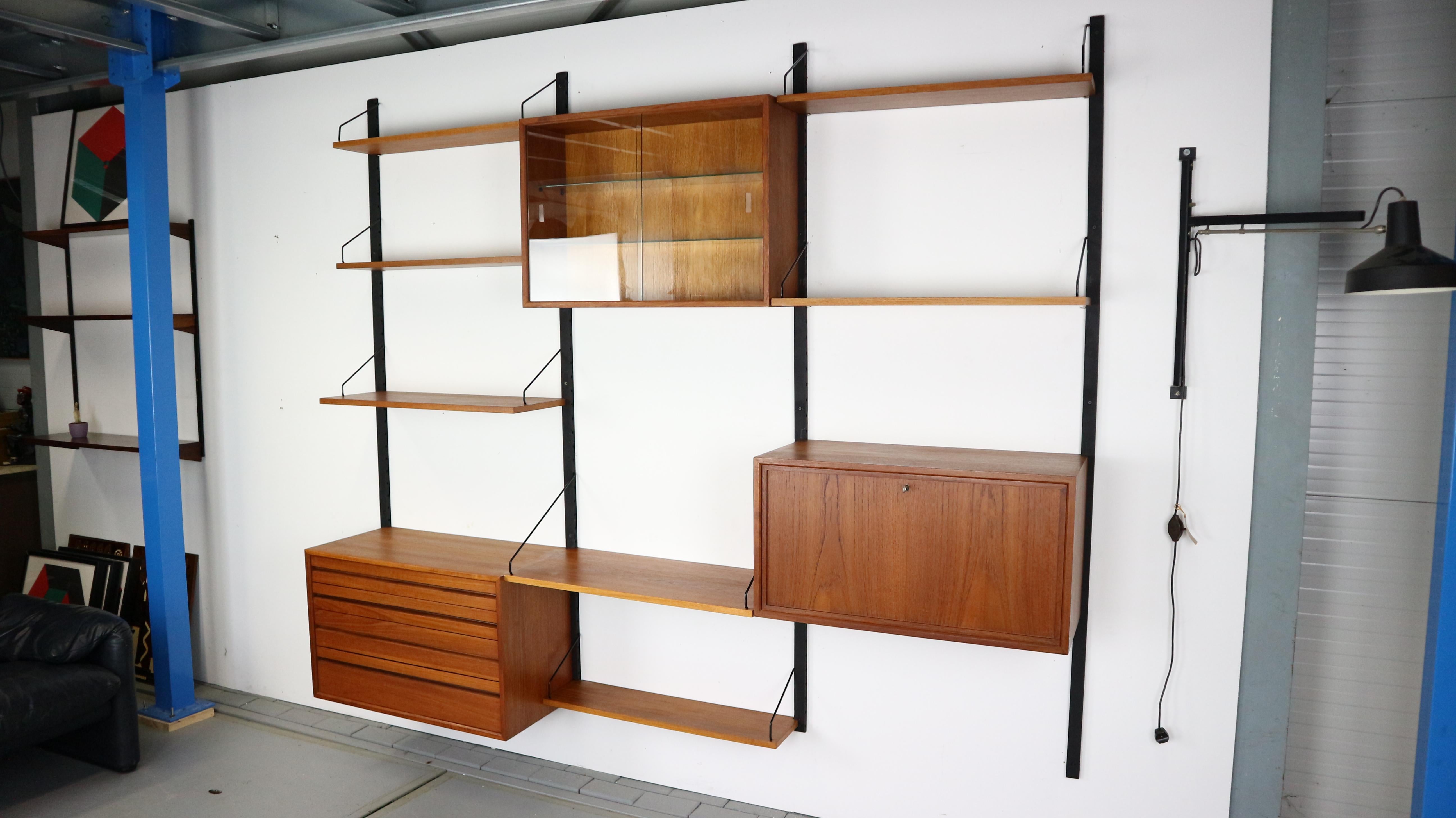 Teak wooden Danish Royal system designed by Poul Cadovius for Cado, Denmark in the 1960s. 
This vintage wall system is made of: 3 wall slats of 200 cm, a cabinet with drawers inside, a cabinet with glass shelve inside, cabinet- writing desk and