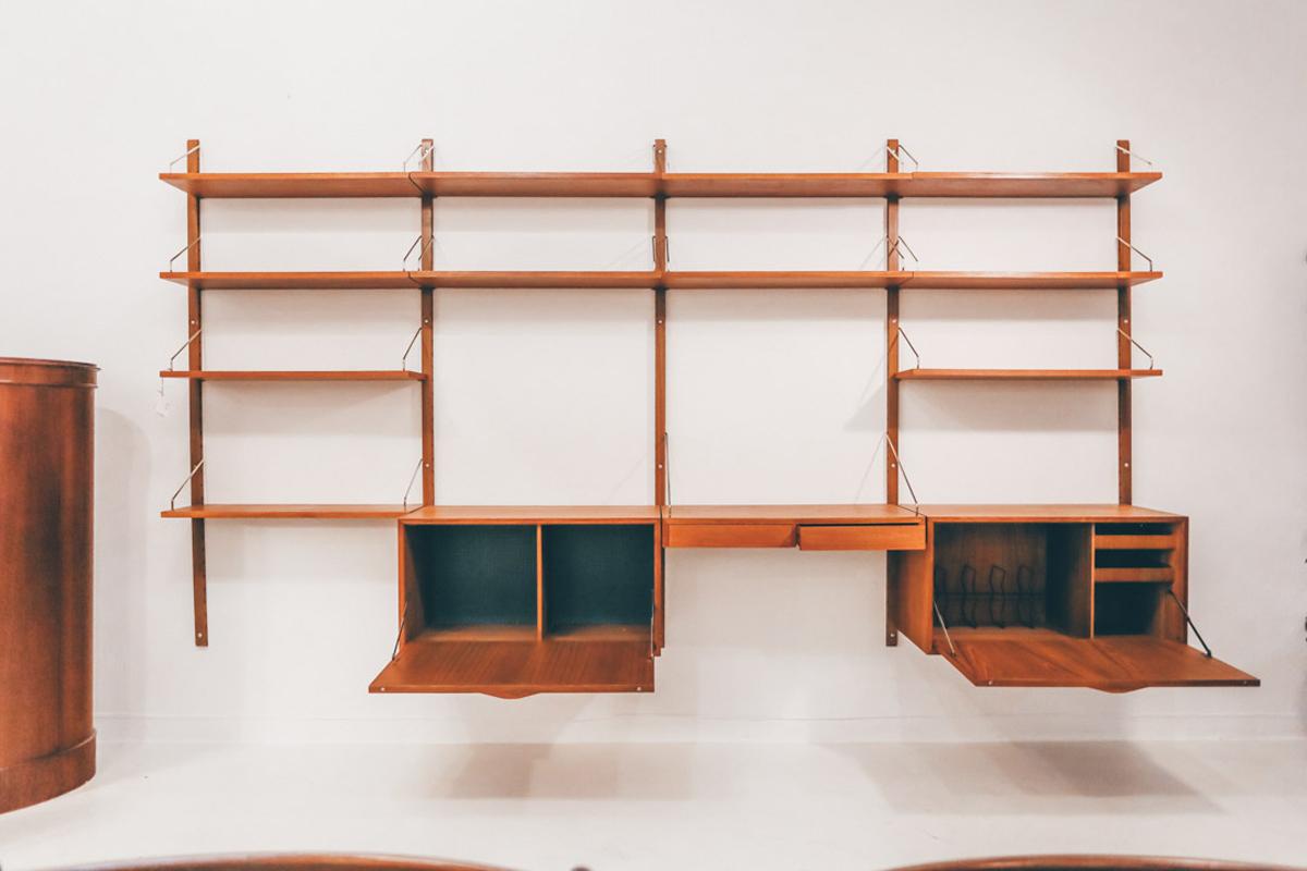 This royal wall unit system in Teak veneer, designed by Poul Cadovius in 1958 was produced by Cado in Denmark. The modular bookcase system consists in 11 shelves, 2 cabinets with key and a desk. The components can be interchanged and placed