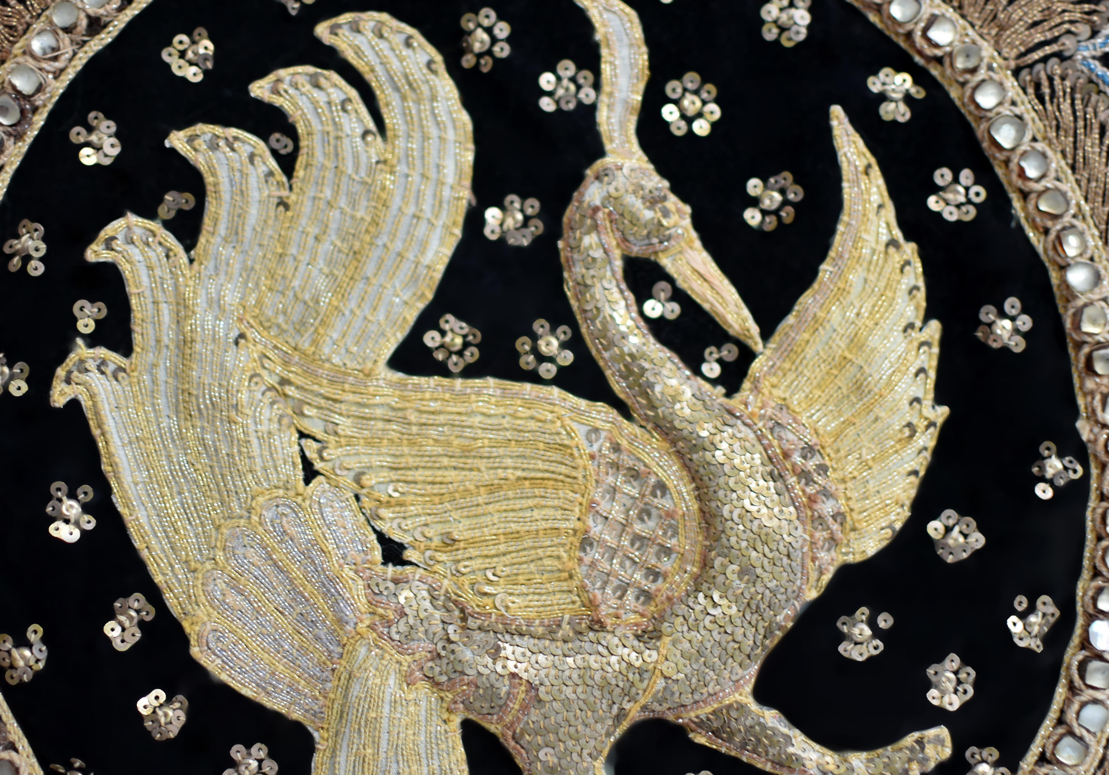 A stunning Thai royal style hand embroidery symbolizing good fortune. The large art piece features a pair of stuffed peacocks embroidered and covered with gold sequins on black velvet background. The medallions are trimmed with gold threads and