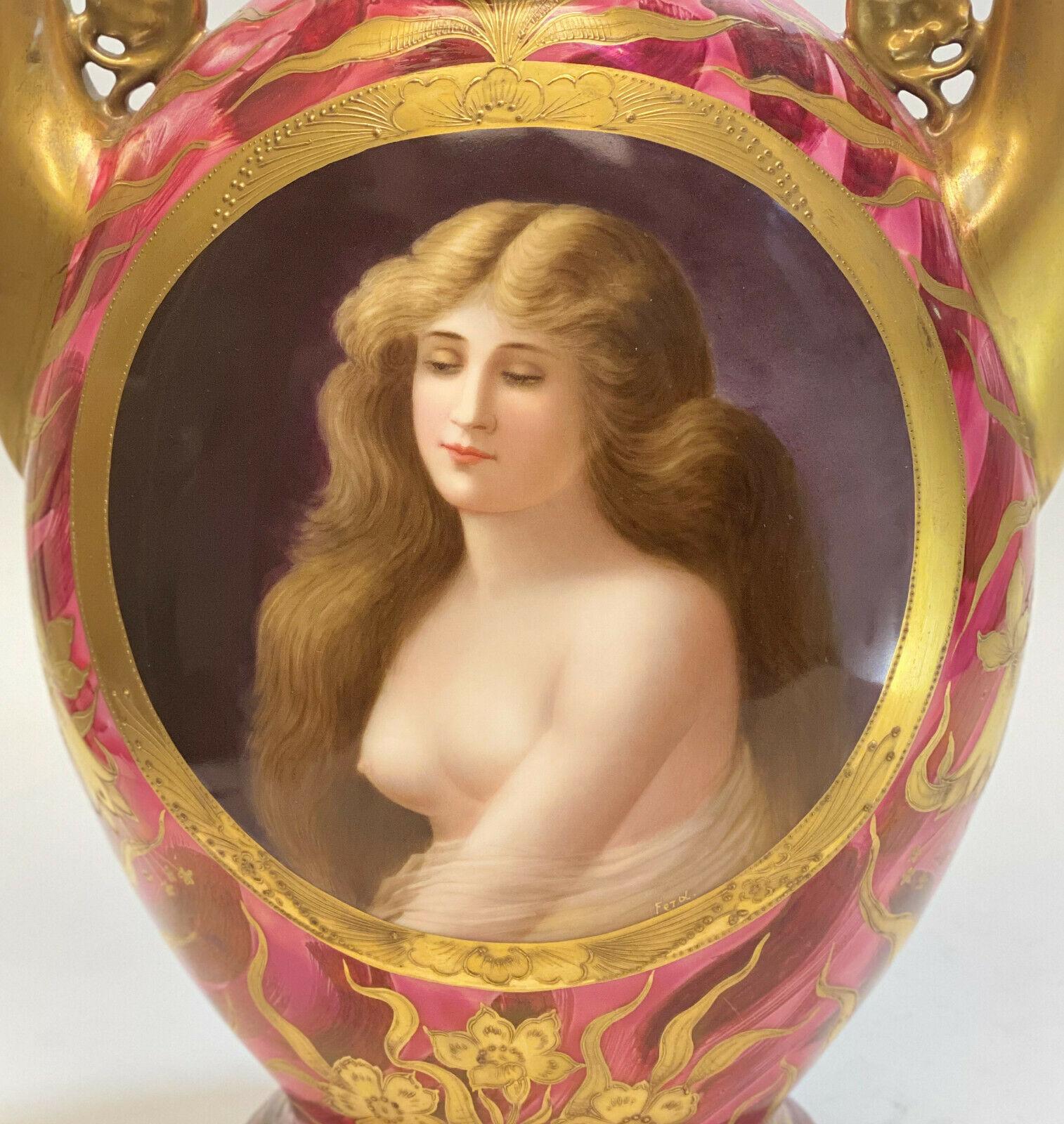 oyal Vienna Art Nouveau hand painted porcelain twin handled lidded urn, circa 1910. A pink and red ground with gold encrusted leaves and floral accents throughout. The center of the urn depicts a partially nude beauty. Artist-signed Ferd. Royal