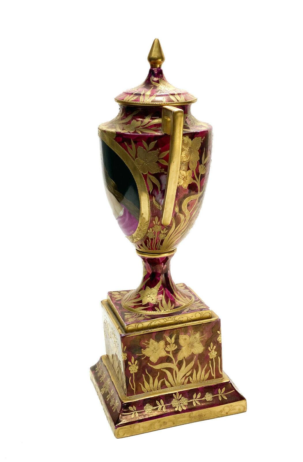 Urne à double poignée en porcelaine peinte à la main Royal Vienna Austria, circa 1900

Un fond rouge bordeaux avec des feuilles et des accents floraux dorés sur toute la surface. La zone centrale représente une beauté partiellement nue, peinte à la
