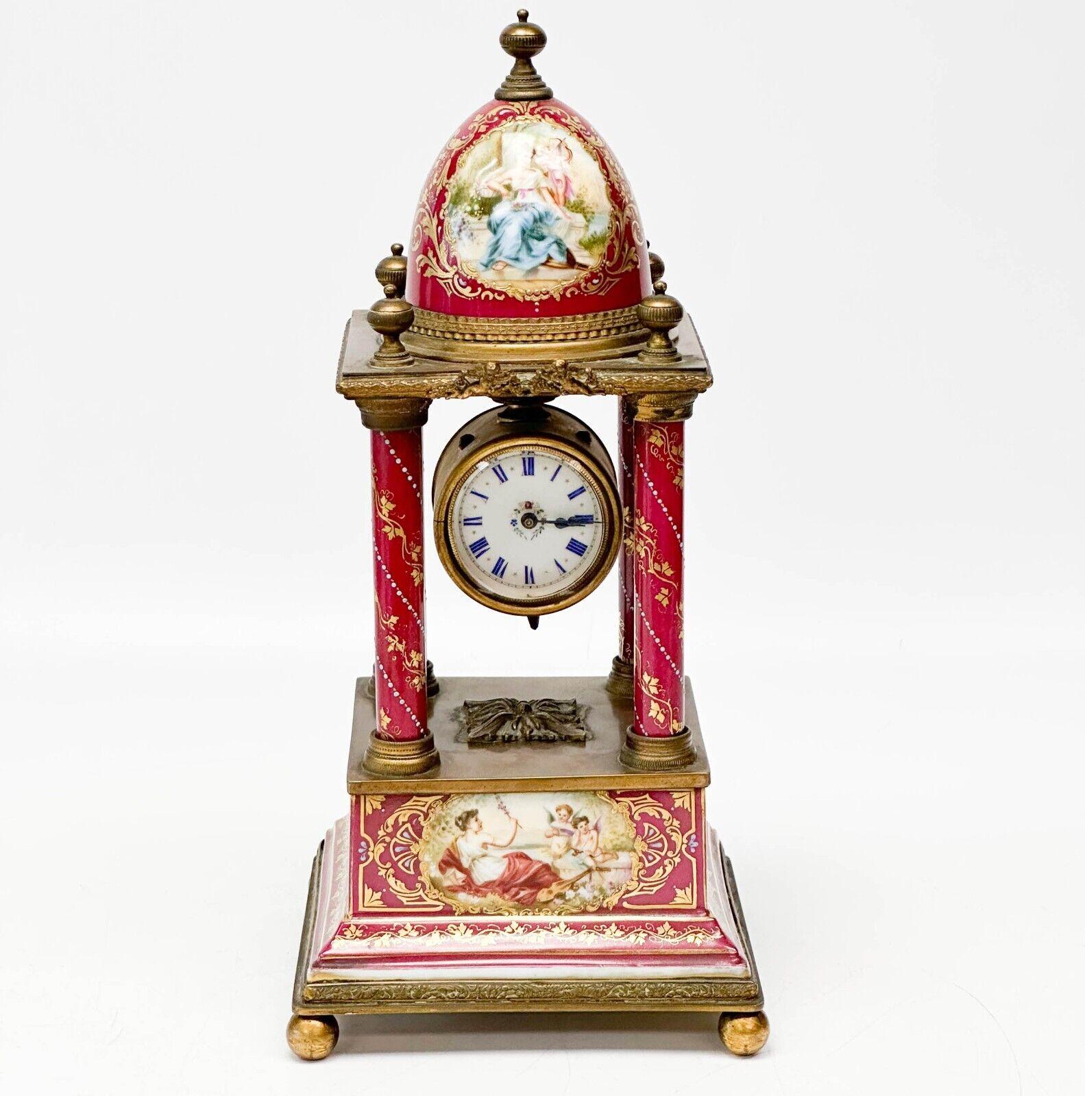  Royal Vienna Austria hand painted porcelain gilt bronze mounted mantle clock, circa 1900. A maroon red ground with gilt foliate decoration and raised blue beaded enamel accents to the sides. Hand painted scenes of figures to the front and to dome.