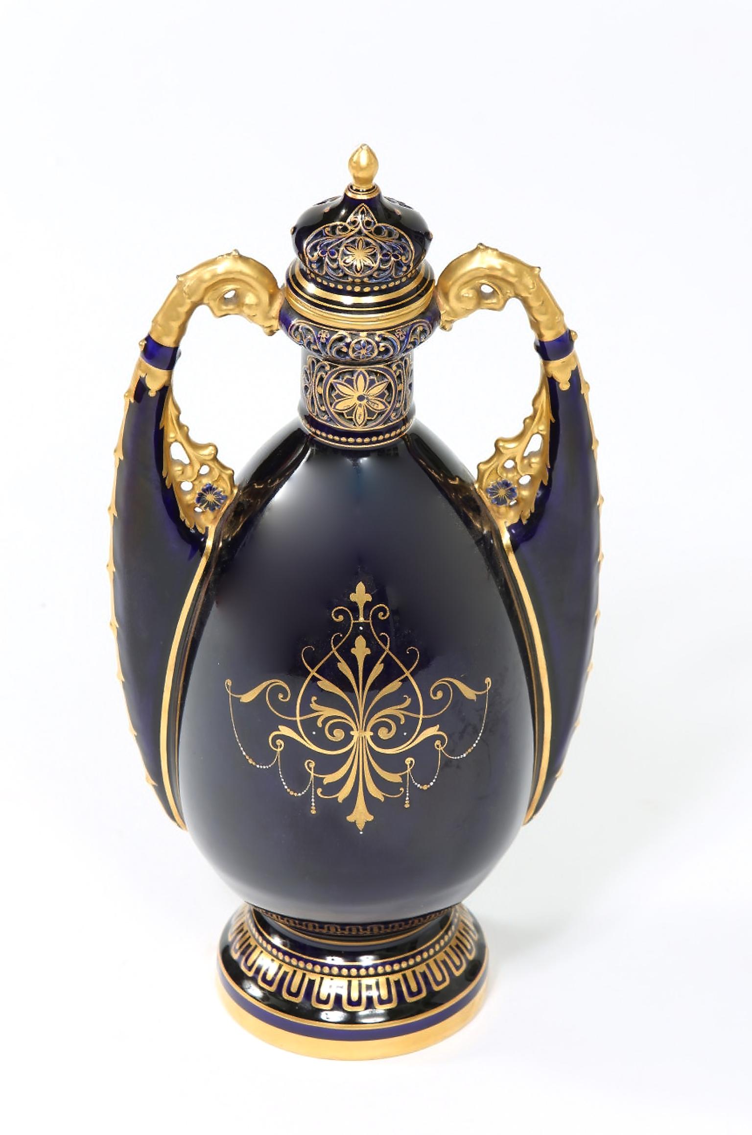 Royal Vienna cobalt blue with gilt gold design details porcelain decorative lidded urn with side handles. The covered urn is in great condition with minor wear consistent with age / use. Maker's mark undersigned. The piece stand about 16 inches high