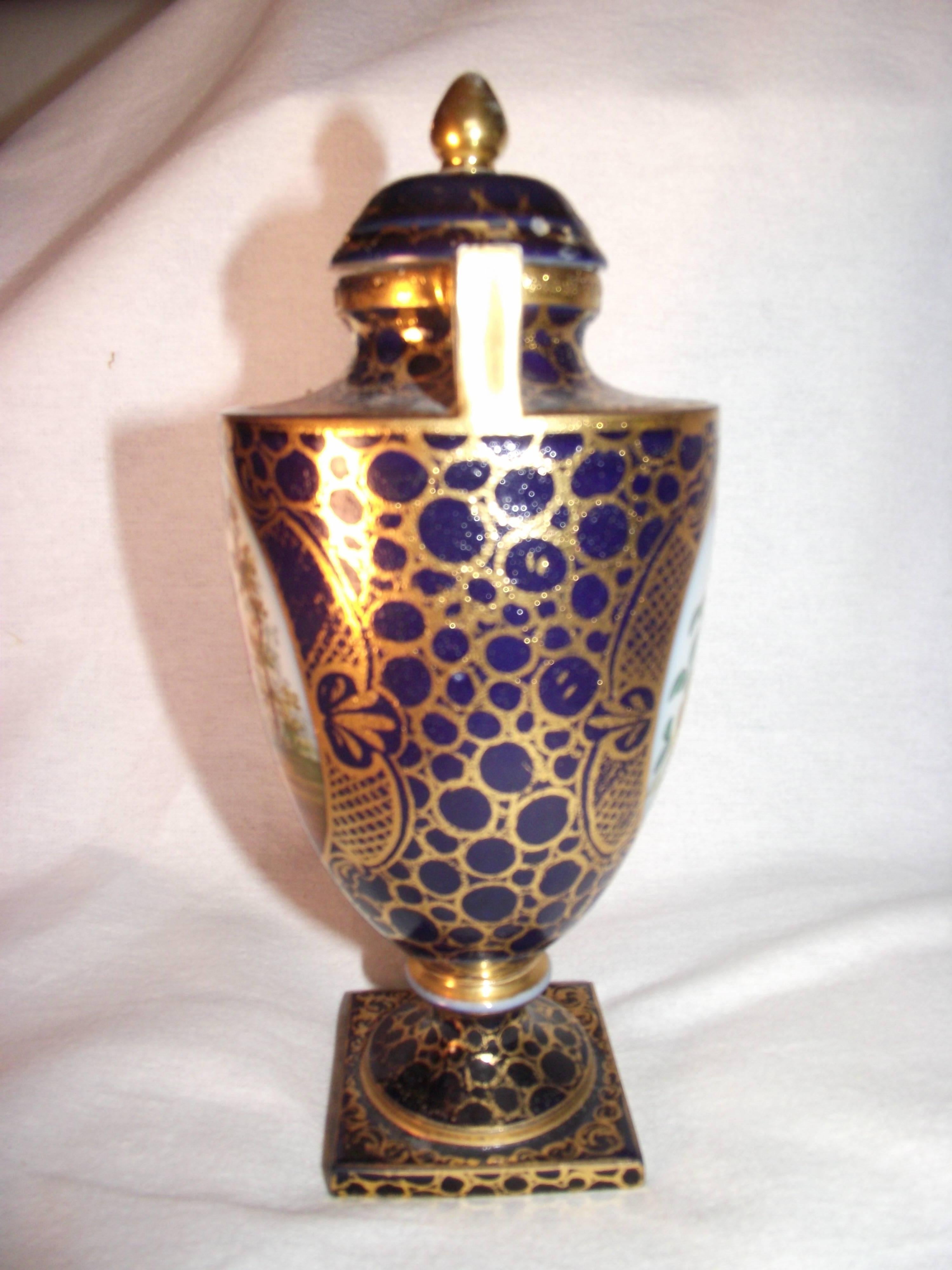 Beautiful little antique hand-painted Royal Vienna urn. It has a courting scene on onside and hand-painted flowers on the other side. It is cobalt blue and metallic gold. It is in very good condition.