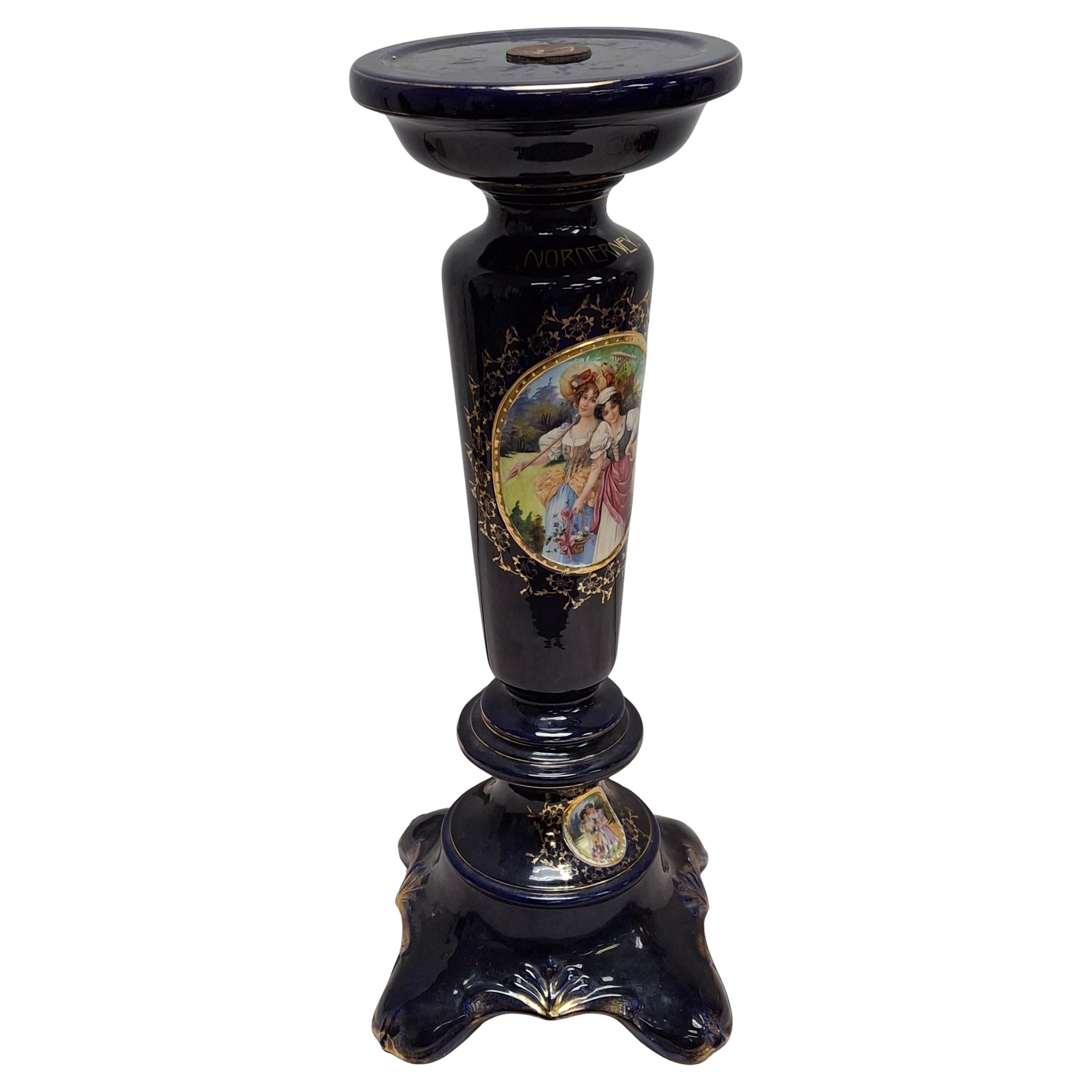 An Early 20th Century Royal Vienna  porcelain pedestal.
 It features a cobalt blue ground with extensive gilding and hand-painted scenes, characteristic of Royal Vienna porcelain. 
The central panel depicts a scene with figures, and the base also