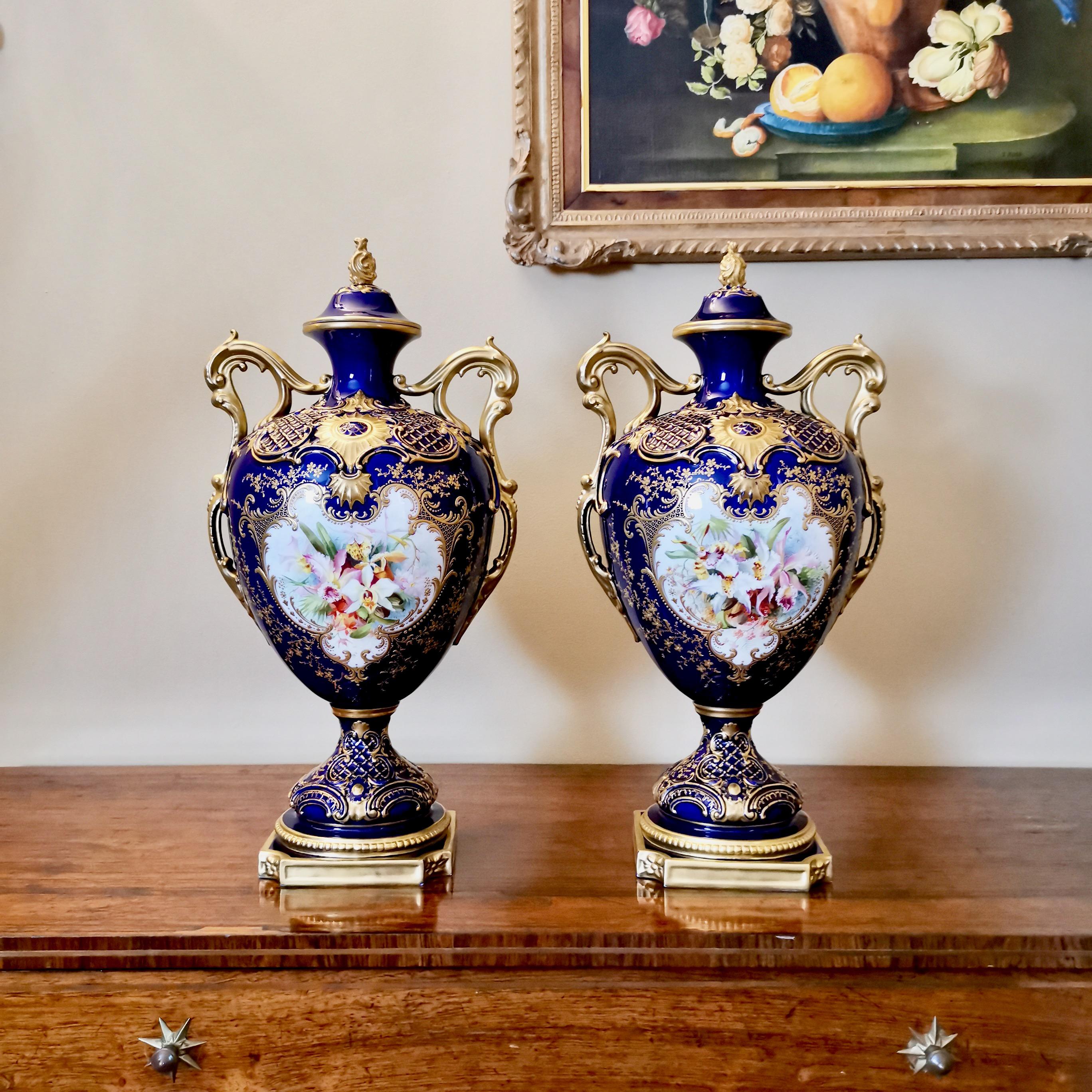 This is a very fine set of two tall lidded vases made by Royal Worcester in 1901. The vases are in the cobalt or mazarine blue and raised gilt style with stunning orchid paintings signed by the famous painter Frank Roberts. 

Worcester was one of