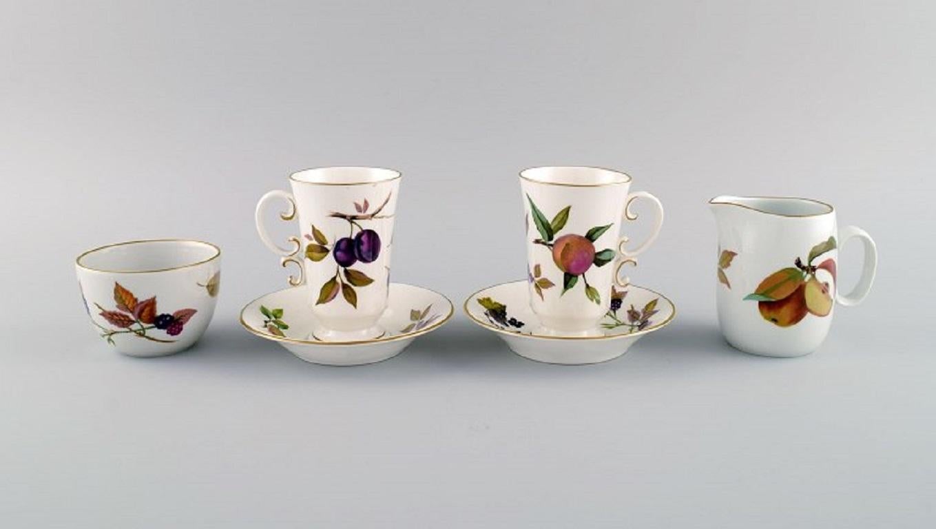 Royal Worcester, England. 
Two Evesham coffee cups with saucers, sugar bowl and cream jug in porcelain decorated with fruits and gold rim. 1980s.
The cup measures: 10 x 6.5 cm.
Saucer diameter: 13 cm.
The sugar bowl measures: 8.5 x 6 cm.
In