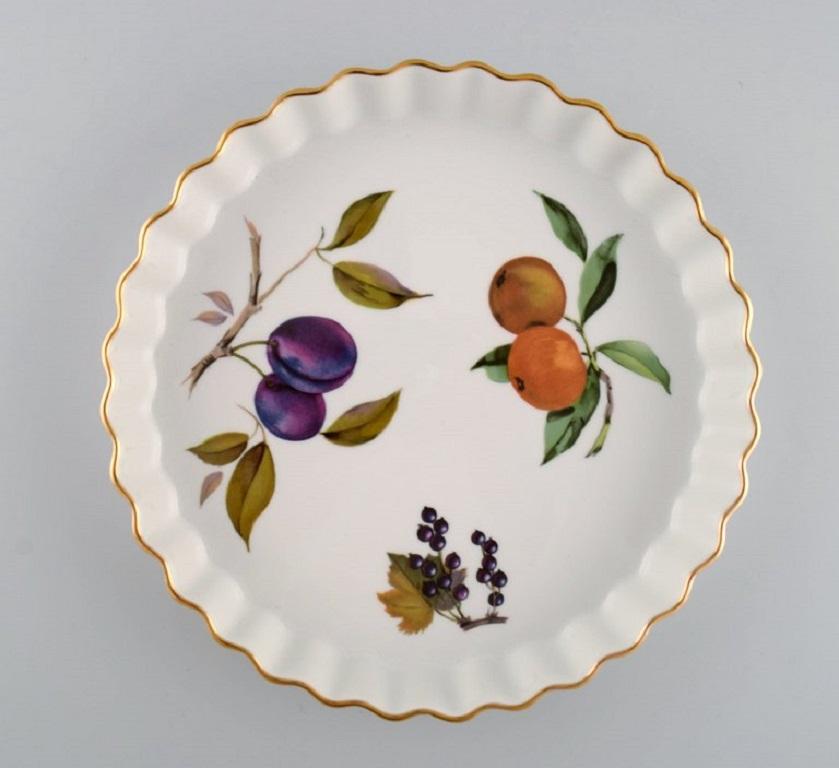 Royal Worcester, England. 
Two Evesham pie dishes in porcelain decorated with fruits and gold rim. 
1980s.
Largest measures: 23 x 3.5 cm.
In excellent condition.
Stamped.