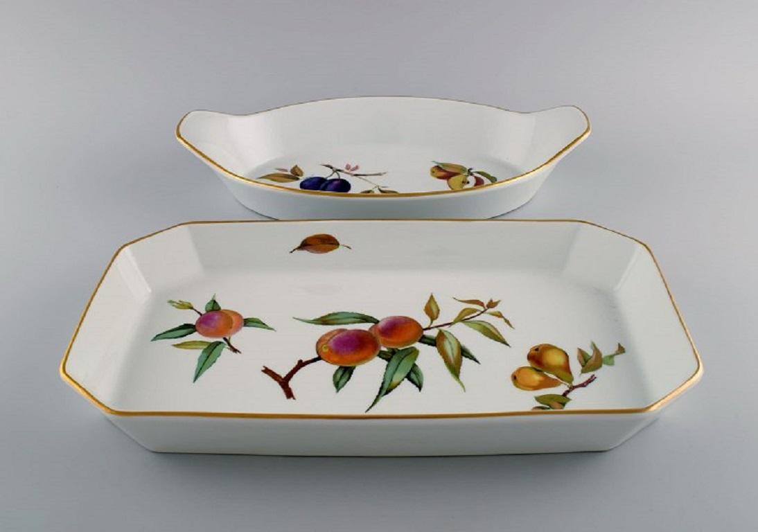 Royal Worcester, England. 
Two Evesham serving dishes in porcelain decorated with fruits and gold rim. 1960/70s.
Largest measures: 39 x 21 x 4.5 cm.
In excellent condition.
Stamped.