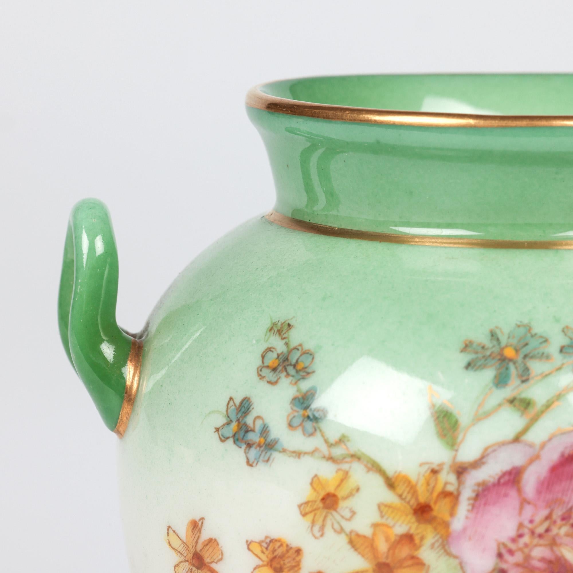 Delizioso vaso in porcellana Royal Worcester a forma di urna con due manici, dipinto a mano con disegni floreali e datato 1905. Il vaso, leggermente invasato, poggia su uno stretto piede rotondo con un corpo bulboso, un collo più stretto e