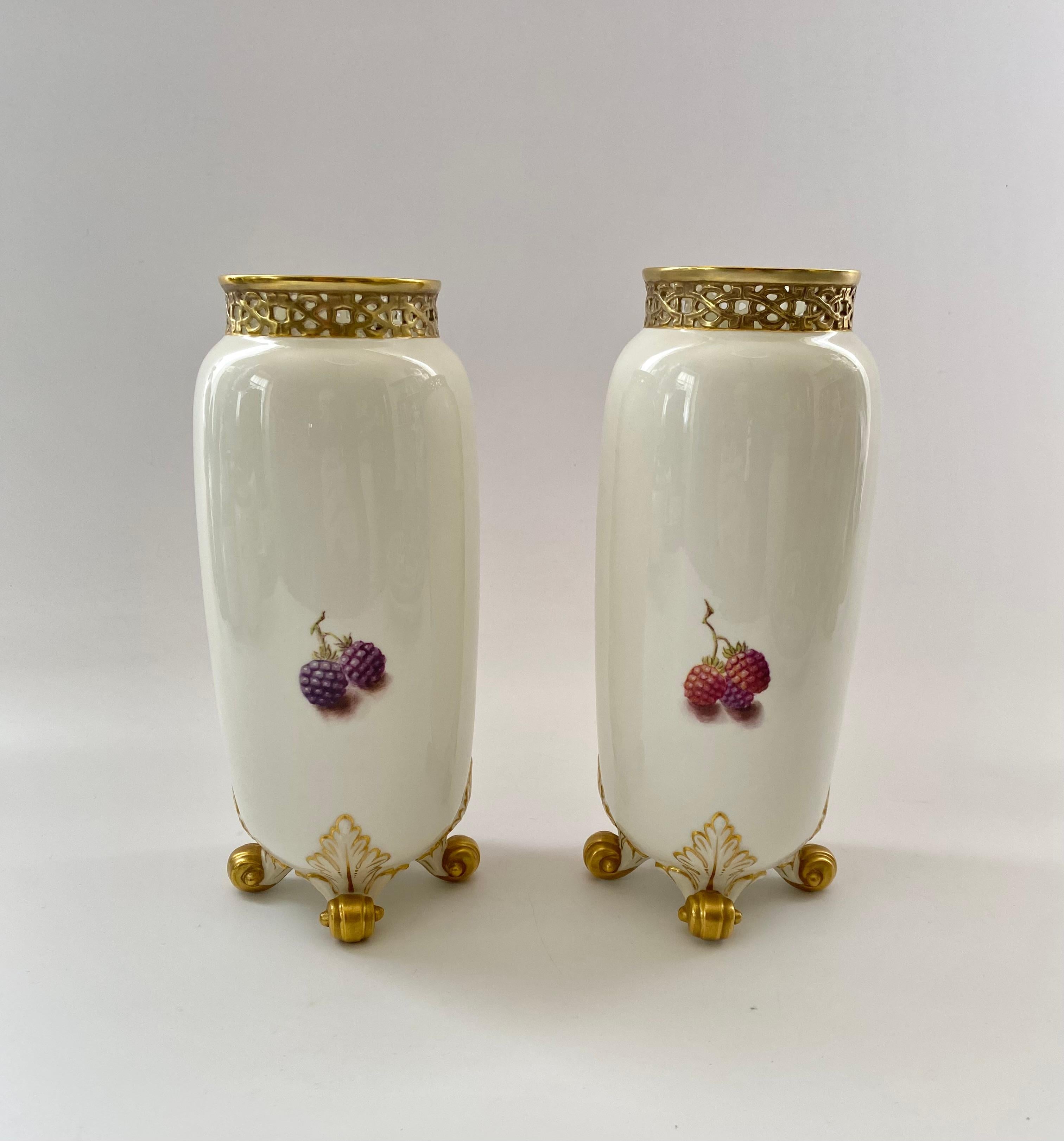Royal Worcester, a pair of ‘Fruit’, vases painted by David J. Scyner, 20th Century. The cylindrical vases, set upon four gilt scroll feet, and having a gilt, reticulated neck. The bodies, hand painted with studies of fruit on a mossy bank.
Signed –