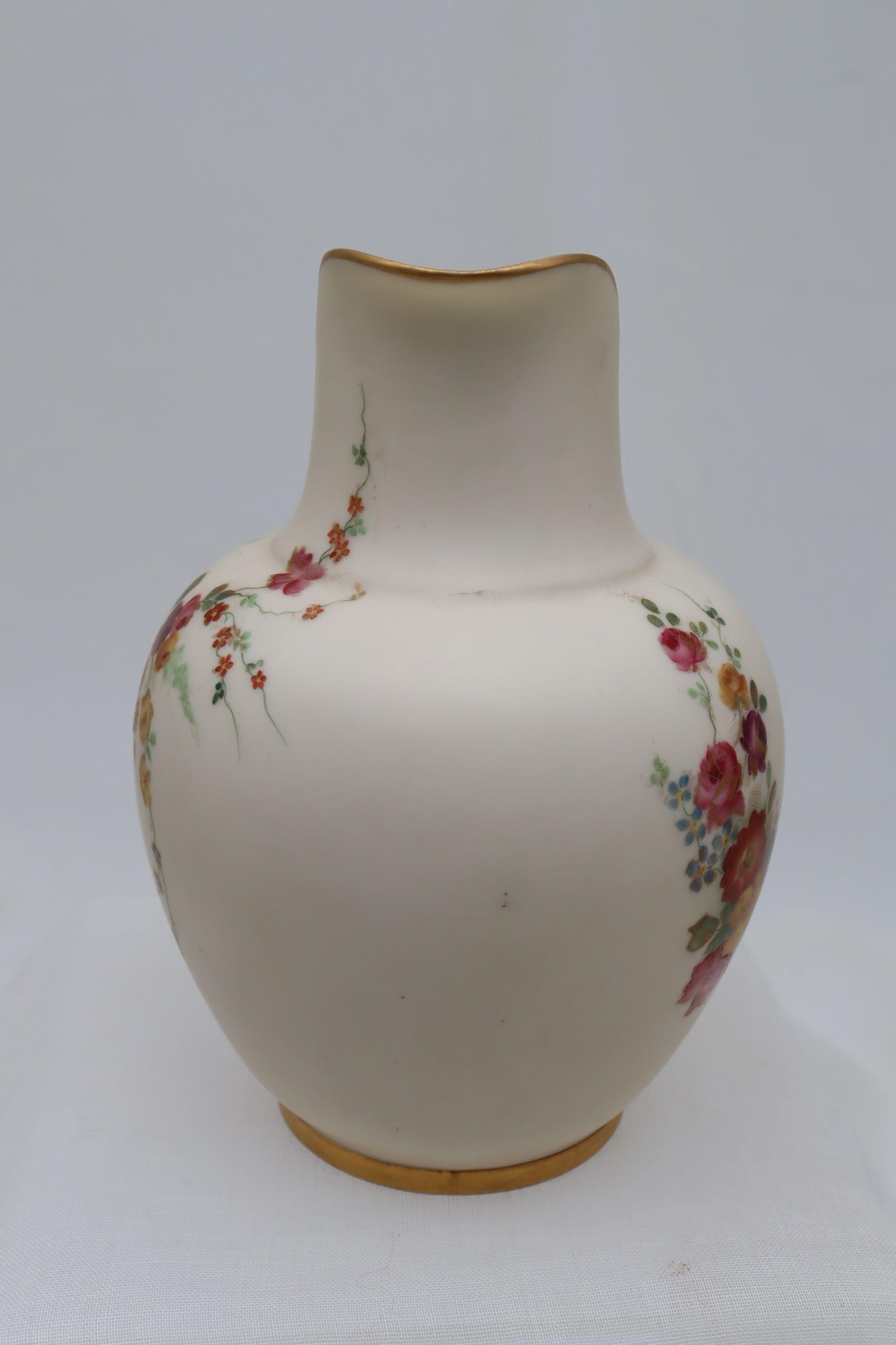 This Royal Worcester porcelain jug is decorated with a lively hand coloured spray of flowers, embellished with gilding, on a cream ground. There is a smaller spray on the reverse. The jug shape is listed as number 1094, which was introduced in 1885,