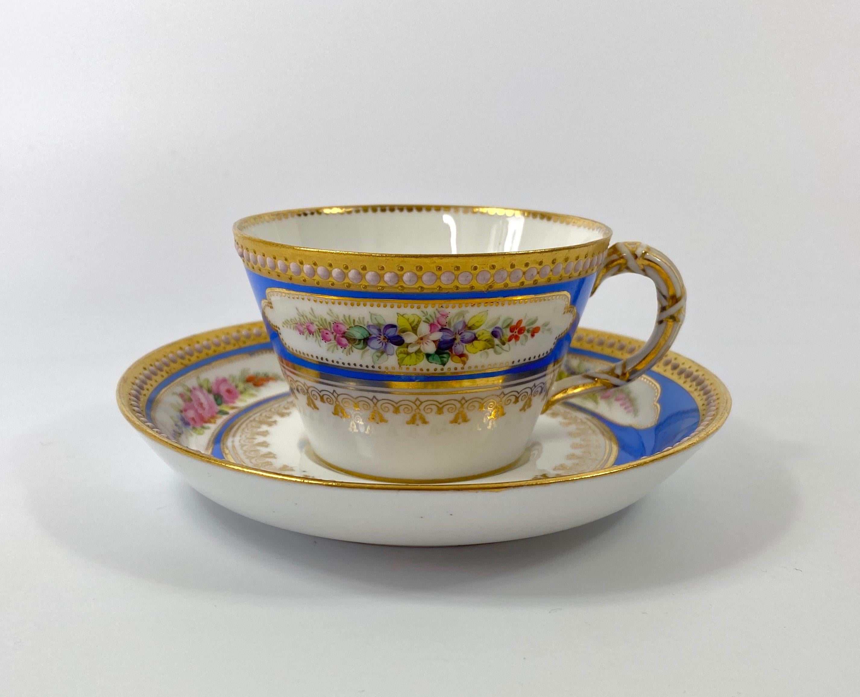 Royal Worcester porcelain ‘Jewelled’ cup and saucer, dated 1876. The conical shaped cup, hand painted with two panels of flowers, upon a light blue ground, and beneath a ‘jewelled’ gilt rim. The interior of the cup, having a gilt dentil rim.
The