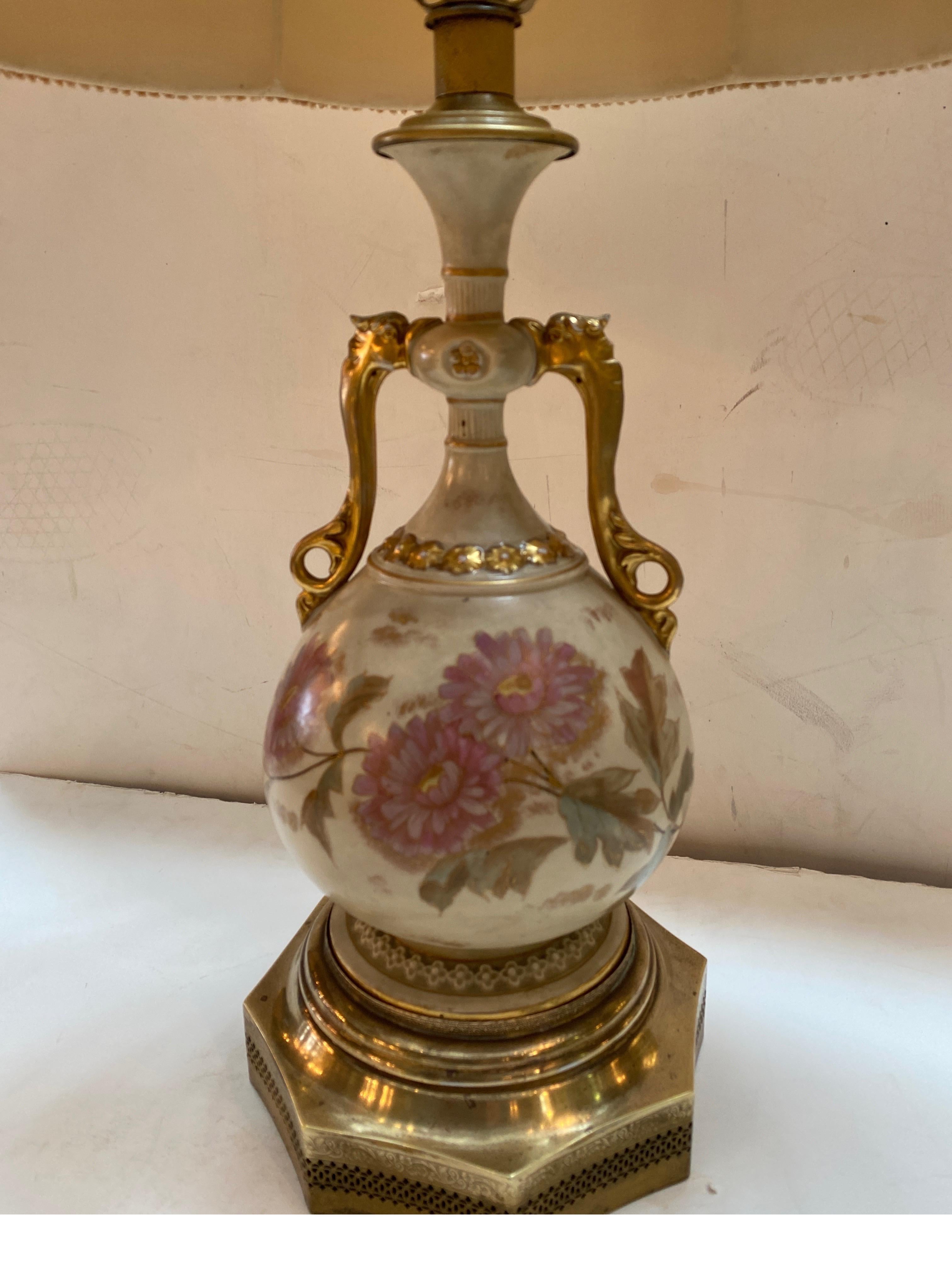 A 19th century English Royal Worchester hand painted vase now as a lamp, The gilt handled floral decorated vase with polished brass base from the around 1880, lamped in the 1920's with a custom brass pierced base. The shade is for photographic