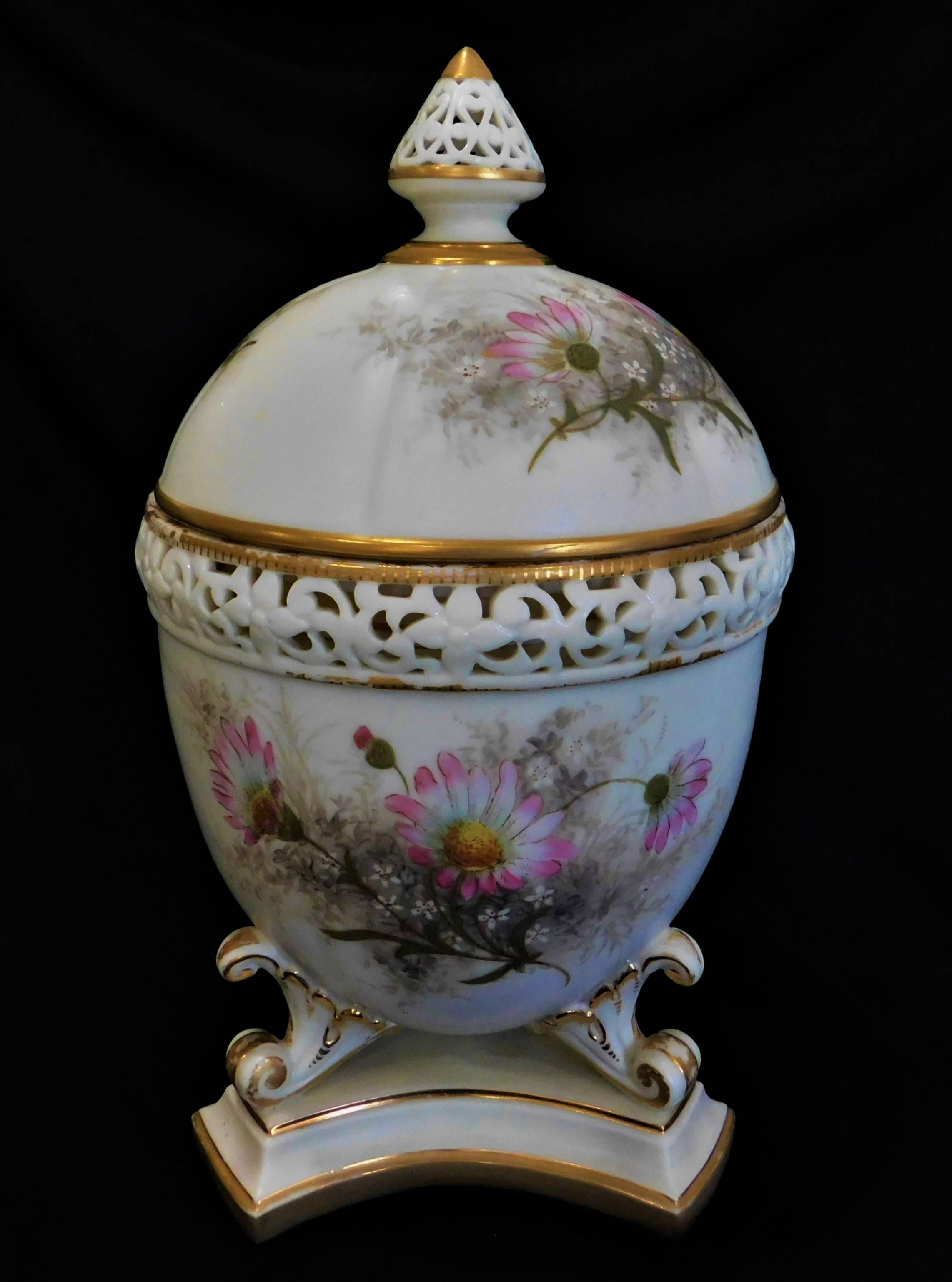 19th century Royal Worcester lidded potpourri porcelain jar, lid and cover, decorated with domed cover and interior lid, surrounded by a pierced border, the body painted with flowers and foliage, on three scrolled feet on trefoil foot.