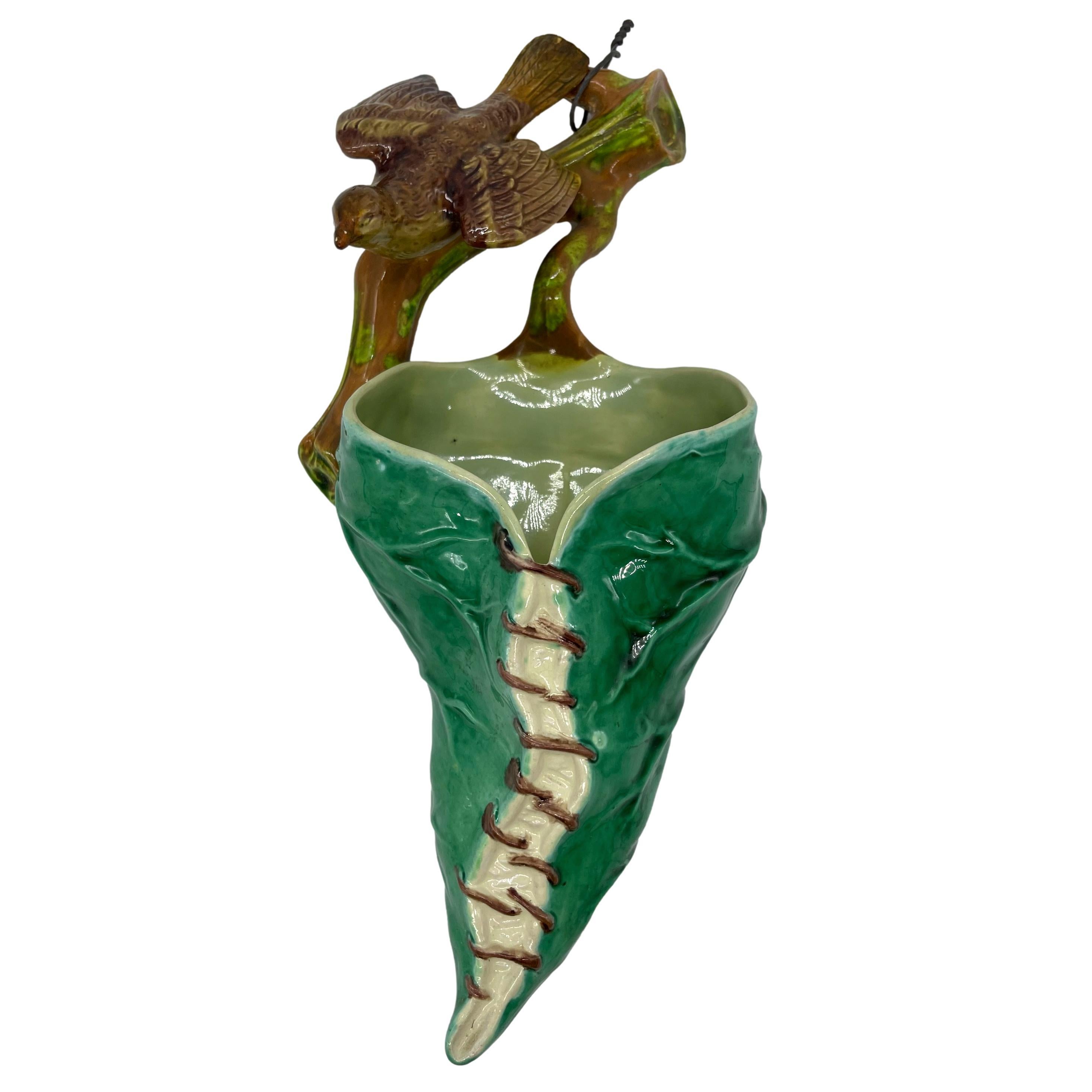 Royal Worcester Majolica Wall Pocket, the vessel molded as a conical-form nest formed by stitched green-glazed leaves, surmounted by a Tailor bird perched on a mossy branch.  Impressed marks to reverse, Royal Worcester factory mark, and design