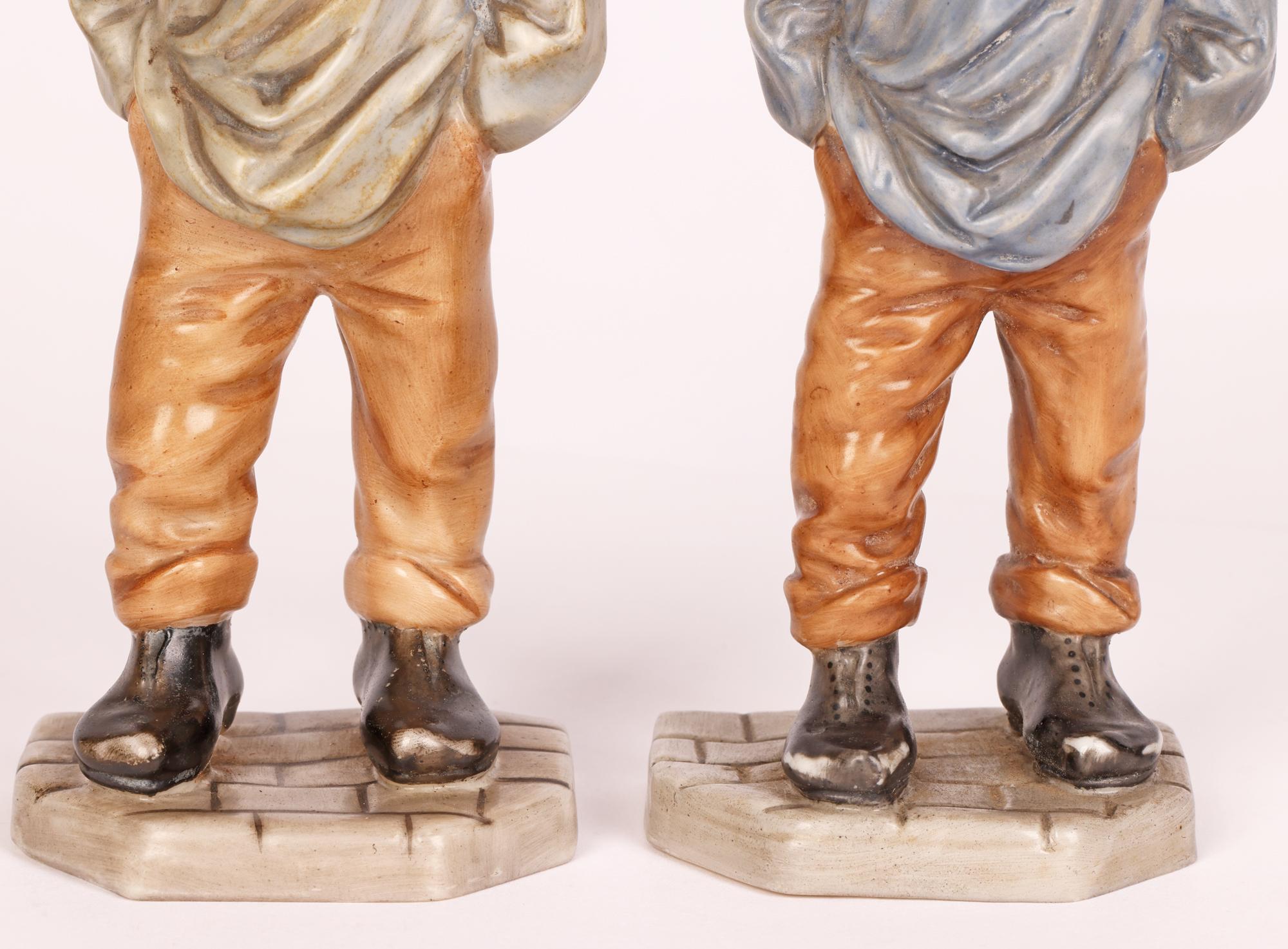 A scarce and delightful pair Royal Worcester porcelain Chinaman figures made as part of a Down & Out series of figures produced as menu holders in 1874. The figures stand on a shaped block work patterned base and wear heavy worn black shoes with an