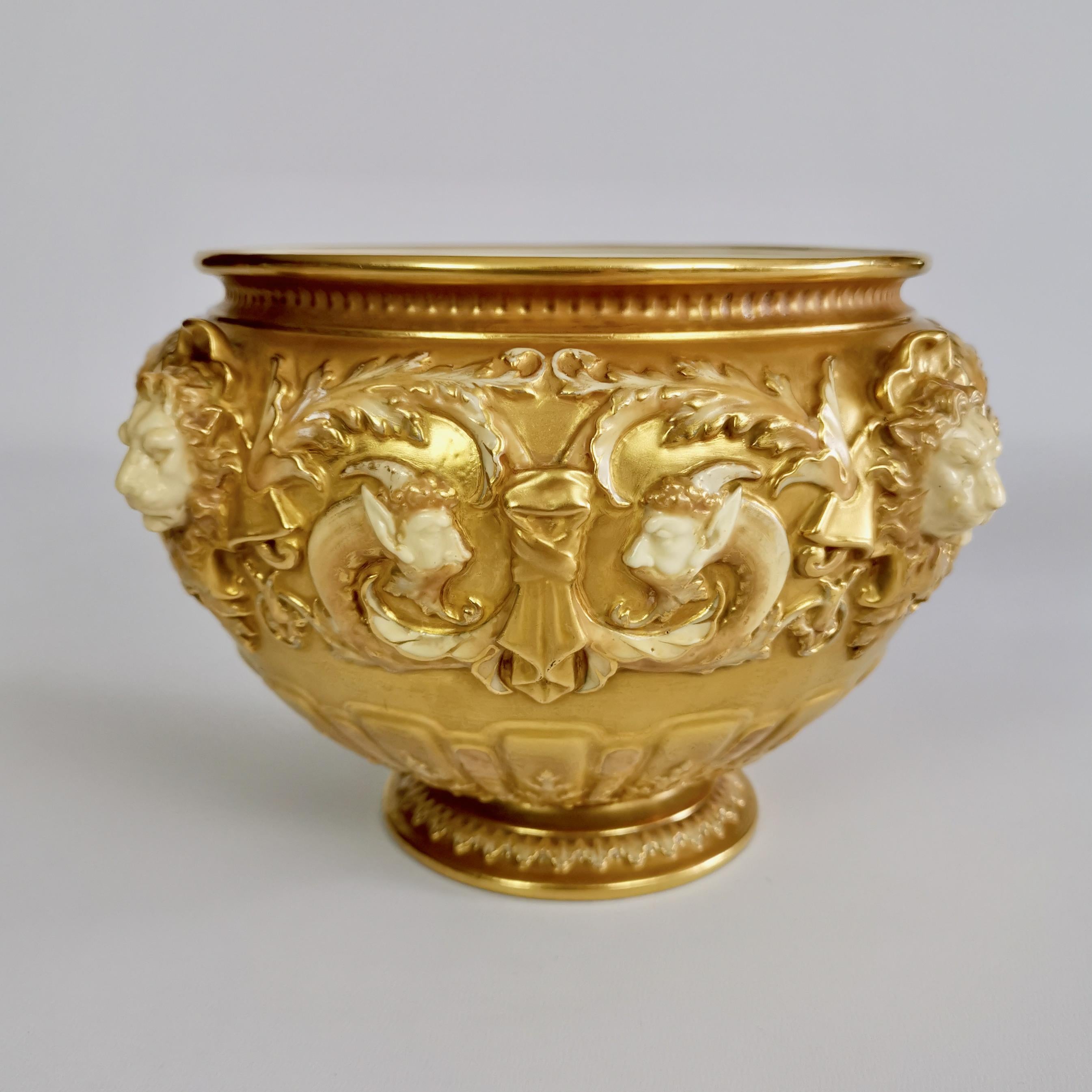 This is a superb jardiniere, or large plant pot, made by Royal Worcester some time between 1892 and 1920. The jardiniere has a gilt ground and stunning moulding containing masks of lion heads and satyrs in the 