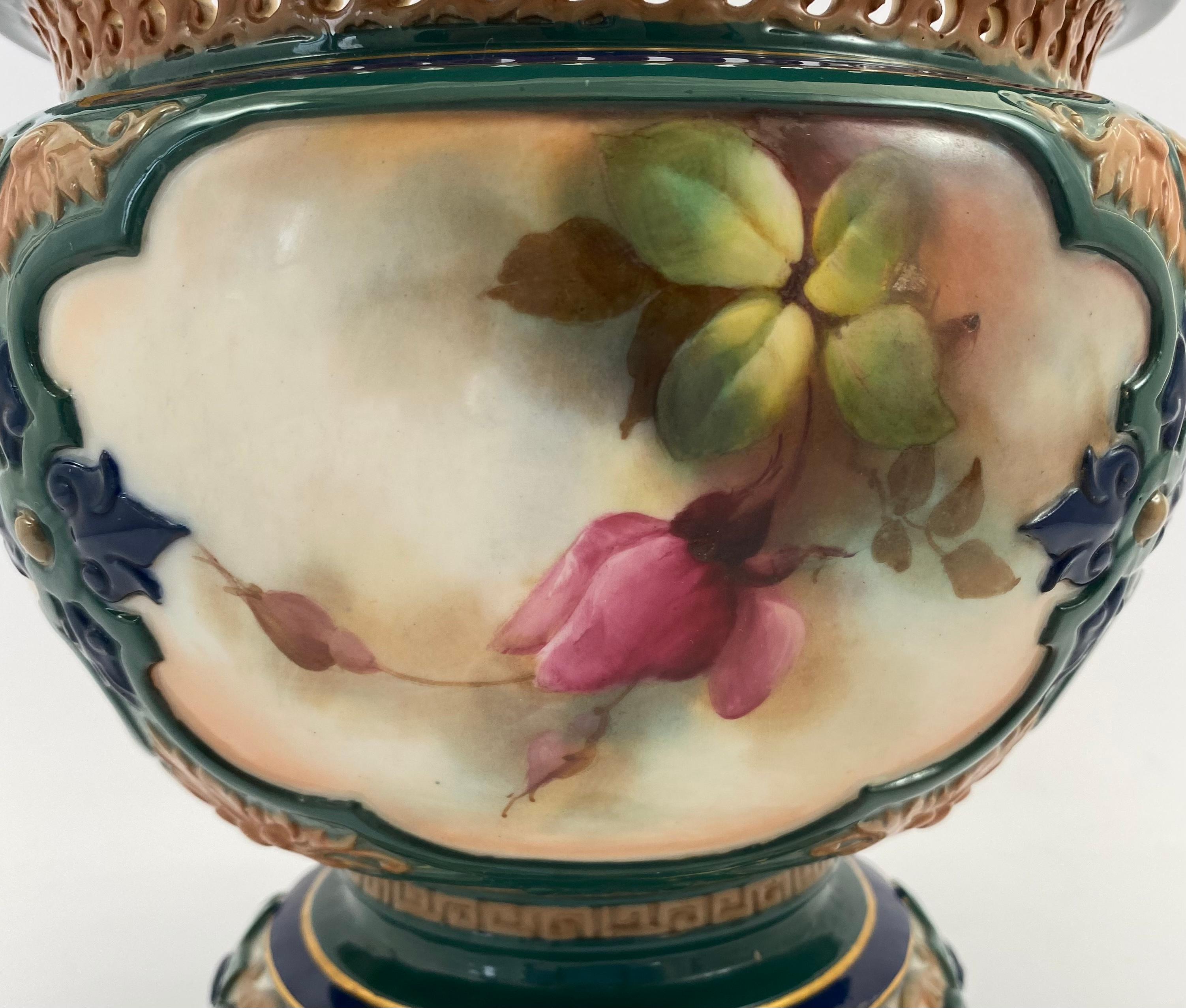 Royal Worcester large, porcelain jardiniere, dated 1907. The Hadley shape jardiniere, having a reticulated rim, and heavily moulded, framed panels. Each panel finely painted with studies of flowering roses.
Set upon a scroll moulded footrim,