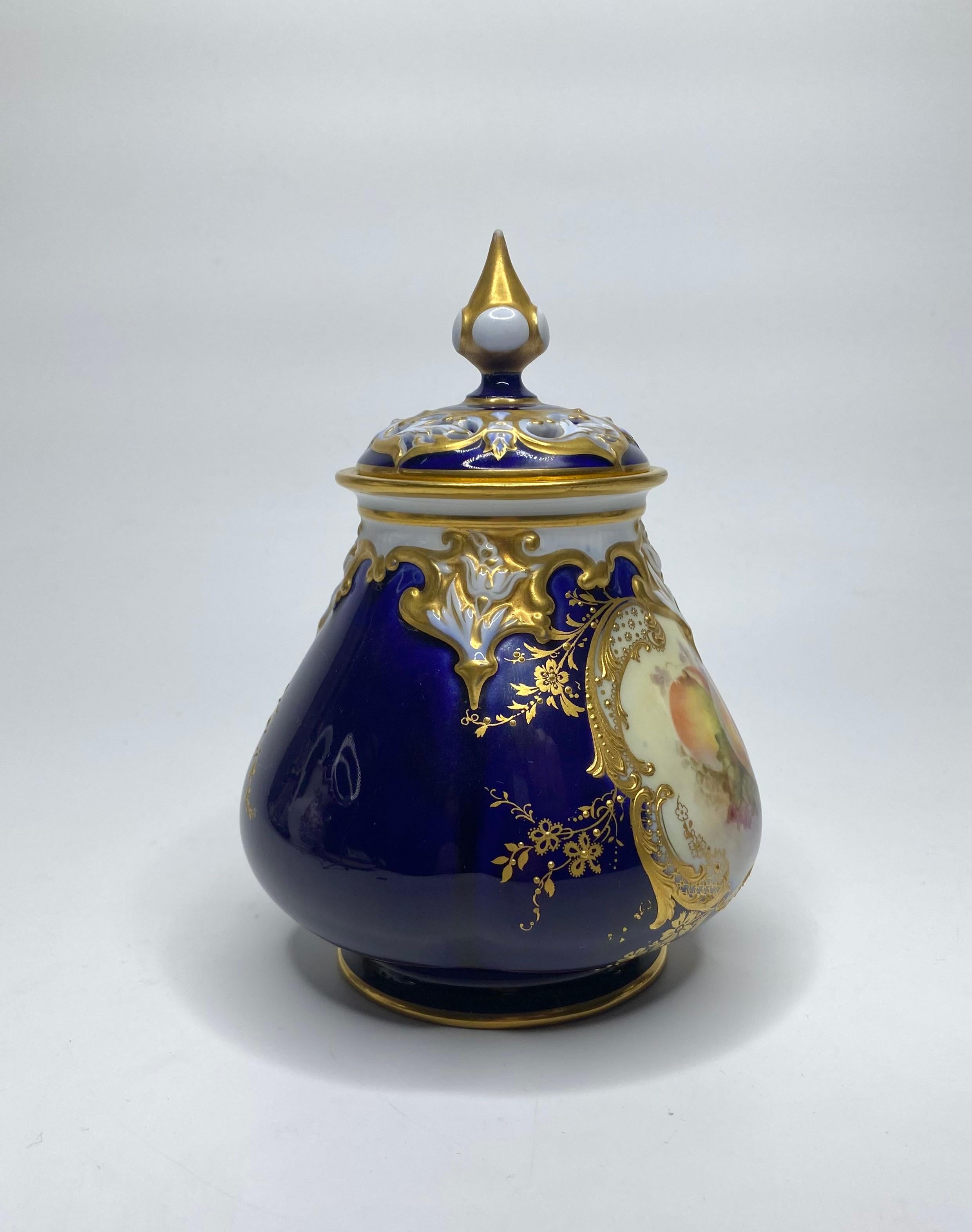 Royal Worcester porcelain pot pourri and cover, painted by Richard Sebright, and dated 1913. Finely painted with a detailed study of fruit amongst blossom and leaves, within an elaborate gilt scroll frame. All upon a cobalt blue ground, further