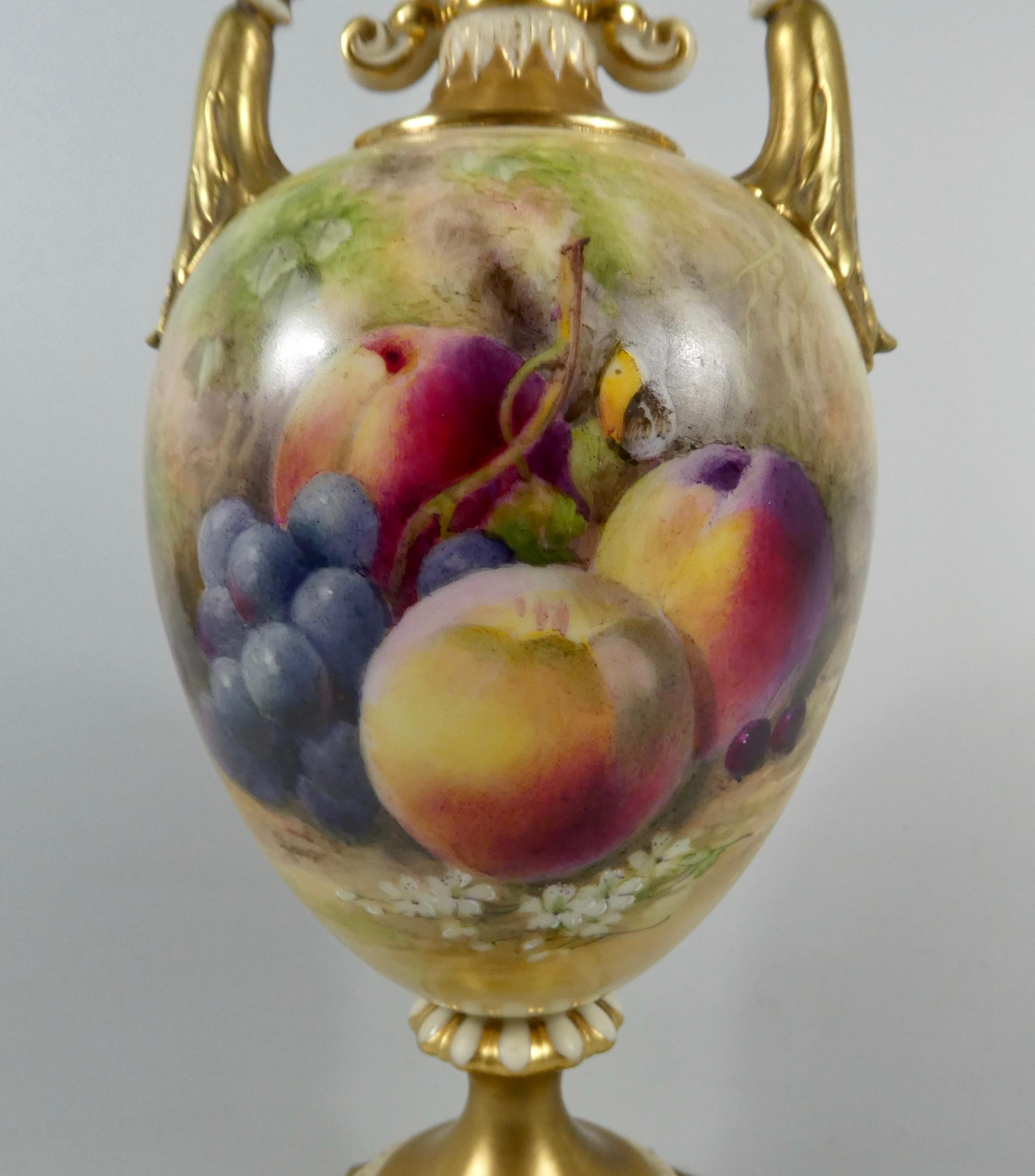 A fine Royal Worcester porcelain vase and cover, dated 1915. Beautifully painted by William Ricketts, with a study of fruit, upon a mossy bank, with a butterfly. The reverse, with a sprig of damsons. Having elaborate acanthus scroll gilt handles