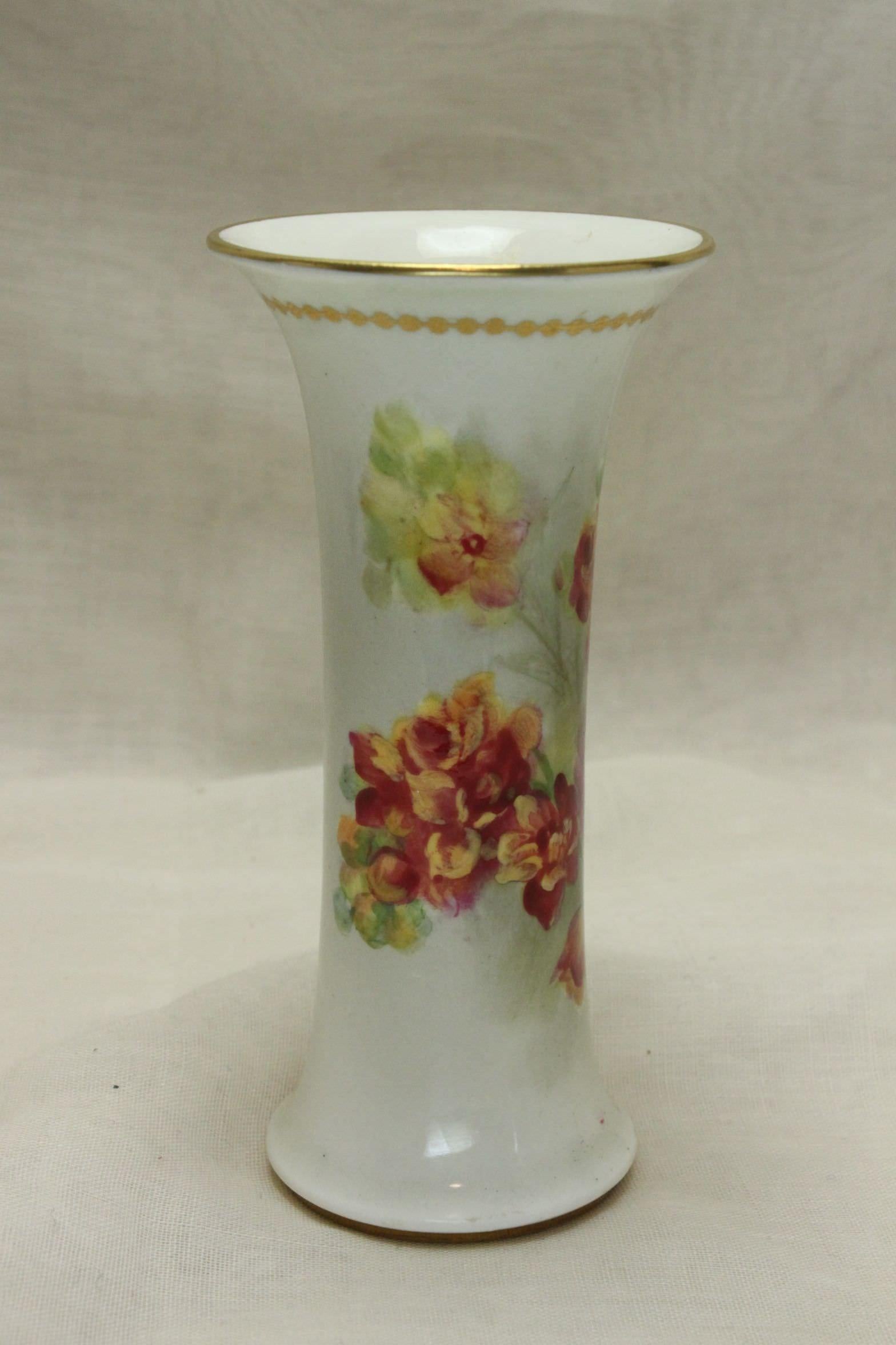 This small Royal Worcester spill vase has been painted by Kitty Blake, who worked at Royal Worcester for 48 years from 1905 to 1953. The decoration is further enhanced with gilding to the foot and the rim, and a line of connected gilt dots just