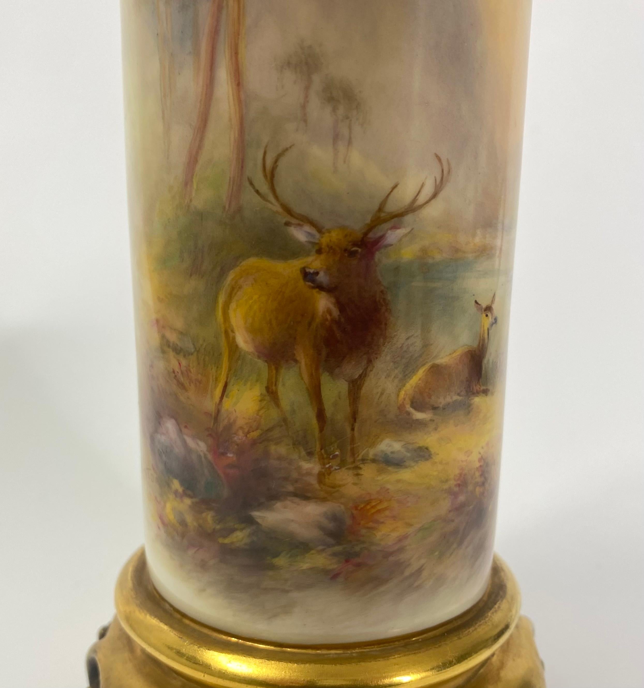 Rare Royal Worcester porcelain ‘Stag’ vase, painted by Harry Stinton, dated 1934. The cylindrical vase, set upon a gilded scroll footrim, and finely painted with a large stag, and a deer in an atmospheric Highland setting of trees, and a loch, in a