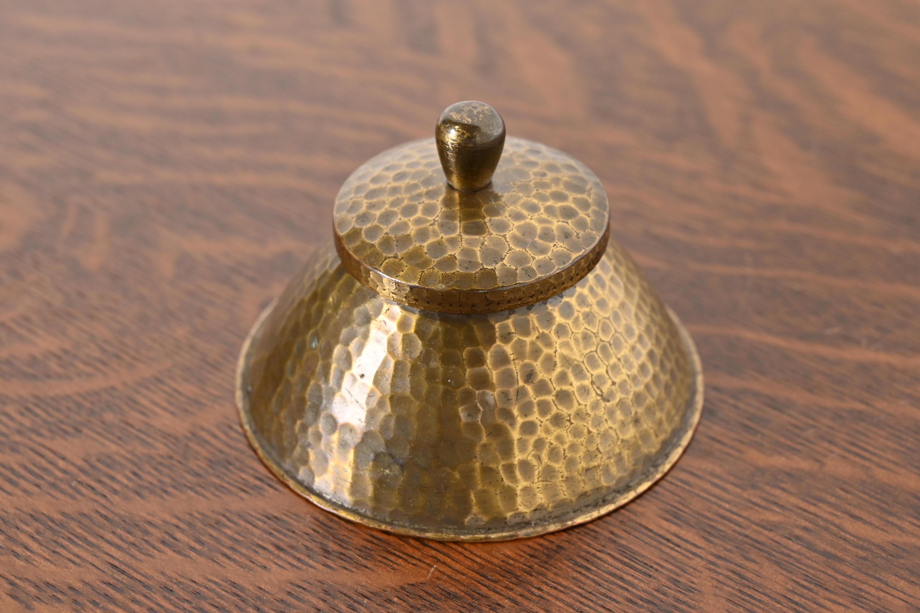 A gorgeous Arts & Crafts period brass finished hand hammered copper inkwell

By Roycroft (signed with impressed orb and cross mark)

USA, Early 20th Century

Measures: 3.5