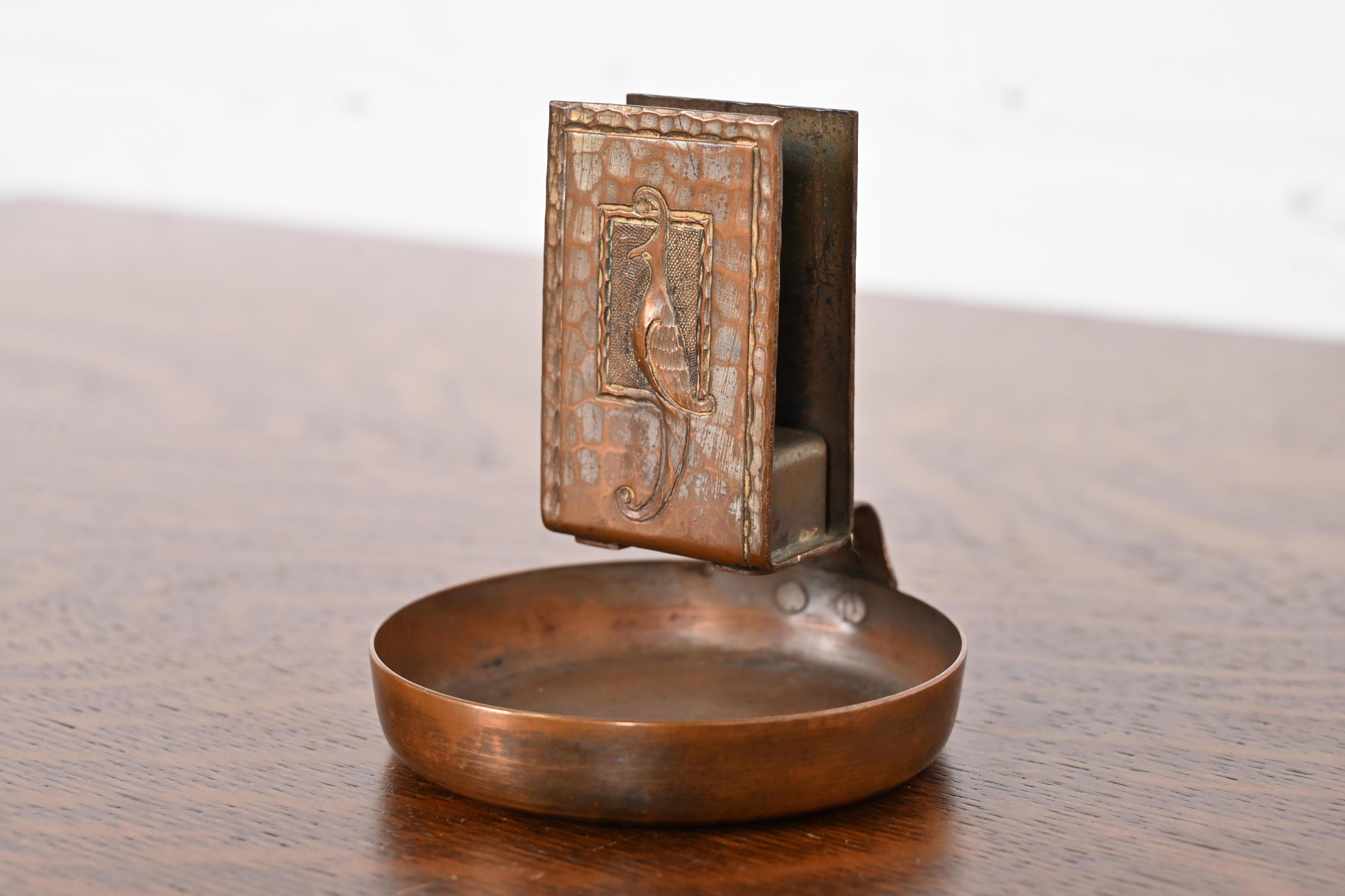 A gorgeous Arts & Crafts period hand hammered copper ashtray and match box holder with bird-of-paradise design

By Roycroft (signed with impressed orb and cross mark)

USA, Early 20th Century

Measures: 3