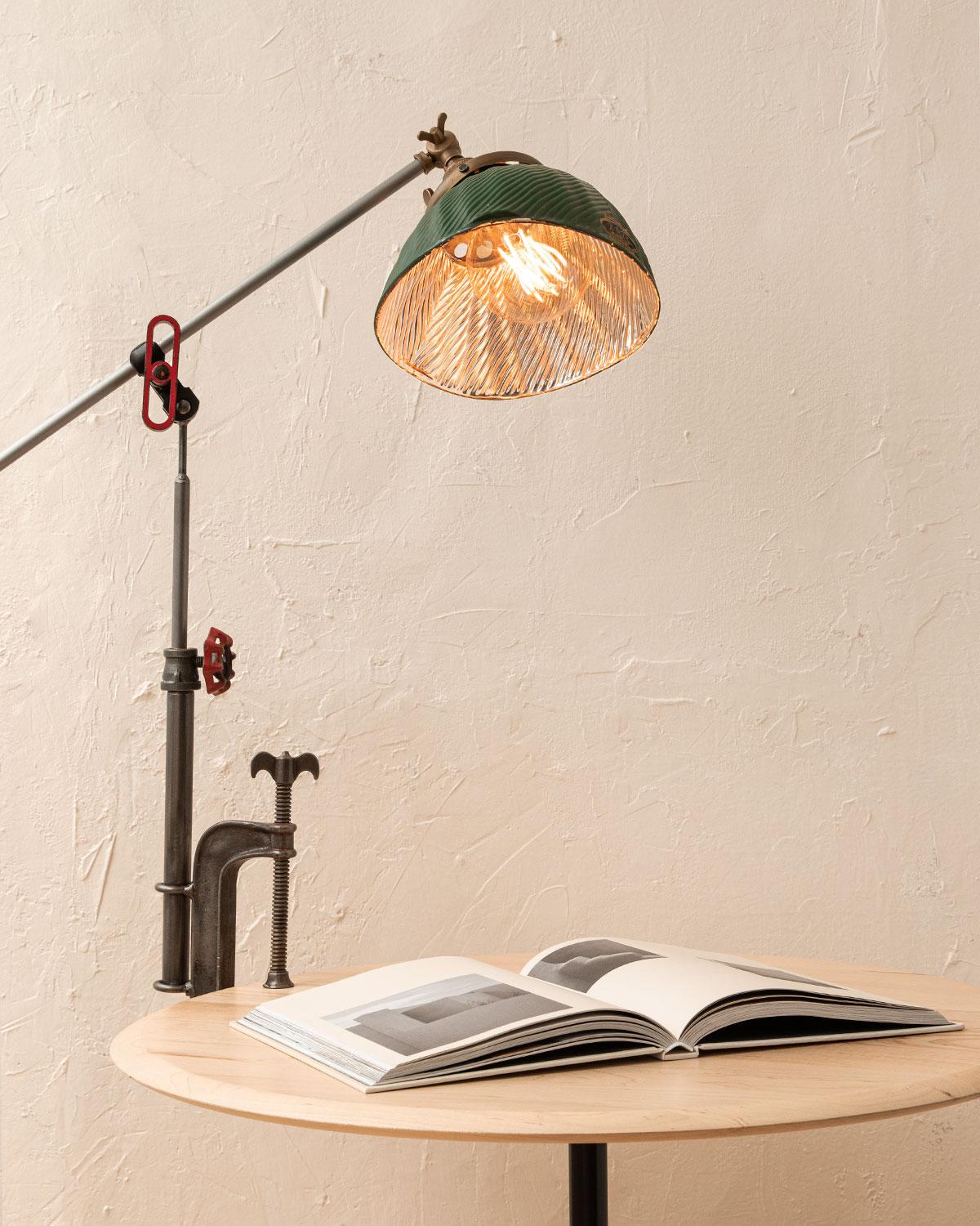 Robert True Ogden's one-of-a-like Found Object Lamps are made by hand in Philadelphia. Crafted from pieces and parts sourced locally and abroad, no two lamps are alike. 

This clamp lamp has a vintage asymmetrical green-painted glass shade with a