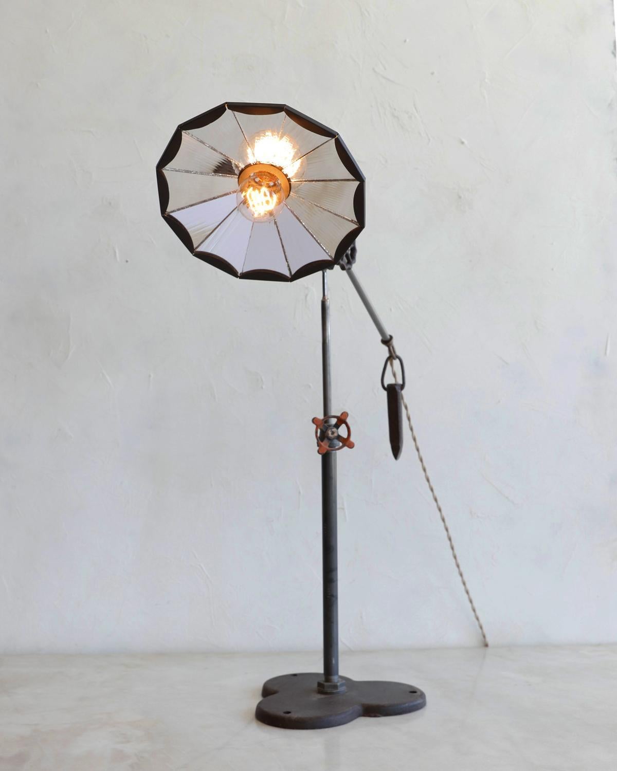 Robert True Ogden's one-of-a-like Found Object Lamps are made by hand in Philadelphia. Crafted from pieces and parts sourced locally and abroad, no two lamps are alike. This table lamp has a ribbon glass mirrored shade with an oil-rubbed brass