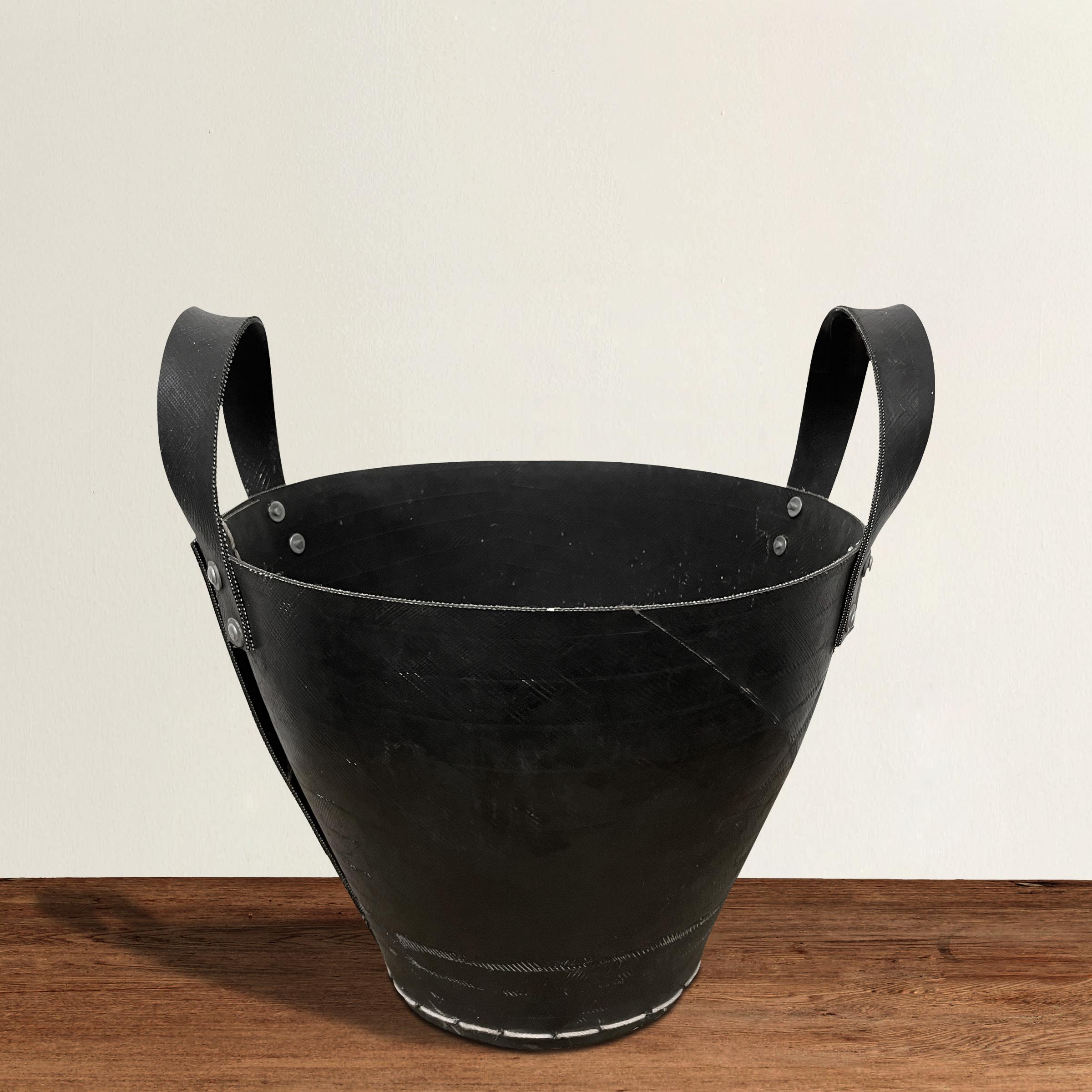 Un secchio a due manici elegante e moderno realizzato con un vecchio pneumatico di gomma, cucito con spago bianco di grosso calibro e rivetti in alluminio. Perfetto come cestino per la carta straccia in bagno o accanto alla scrivania, oppure per