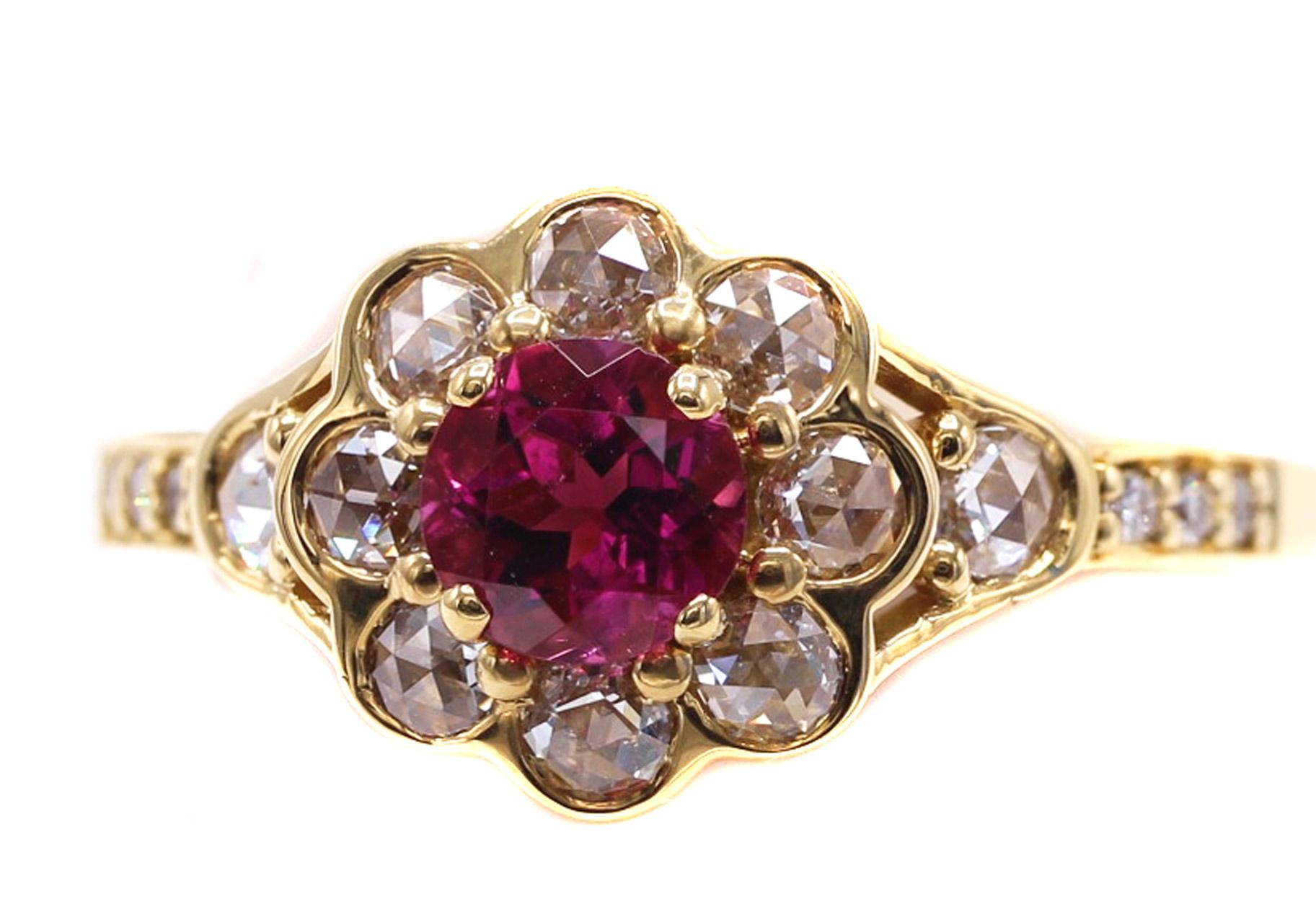 Beautifully designed and masterfully handcrafted this charming 18 Karat yellow gold ring features a vibrant pinkish red round Rubellite as the center piece. Surrounding the center gem are 8 perfectly matched rose cut diamonds bezel set with either