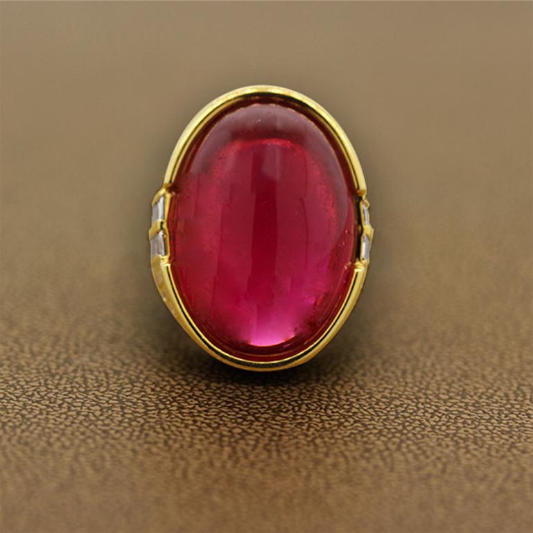 A bold and beautiful cocktail ring featuring a 38.50 carat gem rubelite tourmaline. The oval shaped cabochon tourmaline is set in a half-bezel setting and surrounded by 3.69 carats of glistening colorless diamonds. The two sides of the ring have two