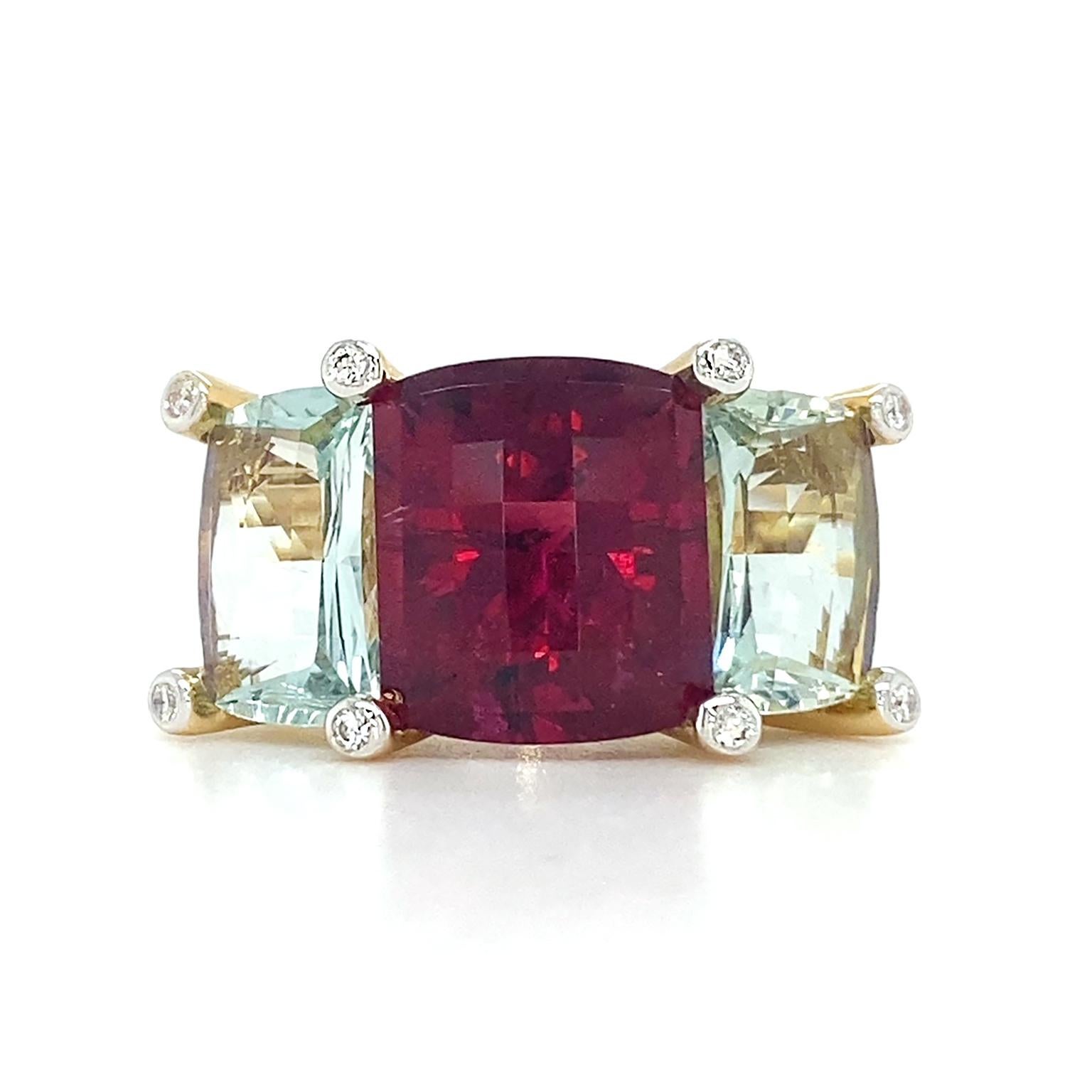 Deep hue rests at the heart of this ring. The central jewel is a dark red rubellite with a hint of purple. It’s cut into a cushion and set between four corner prongs tipped with round brilliant cut diamonds. Flanking the rubellite are pastel green