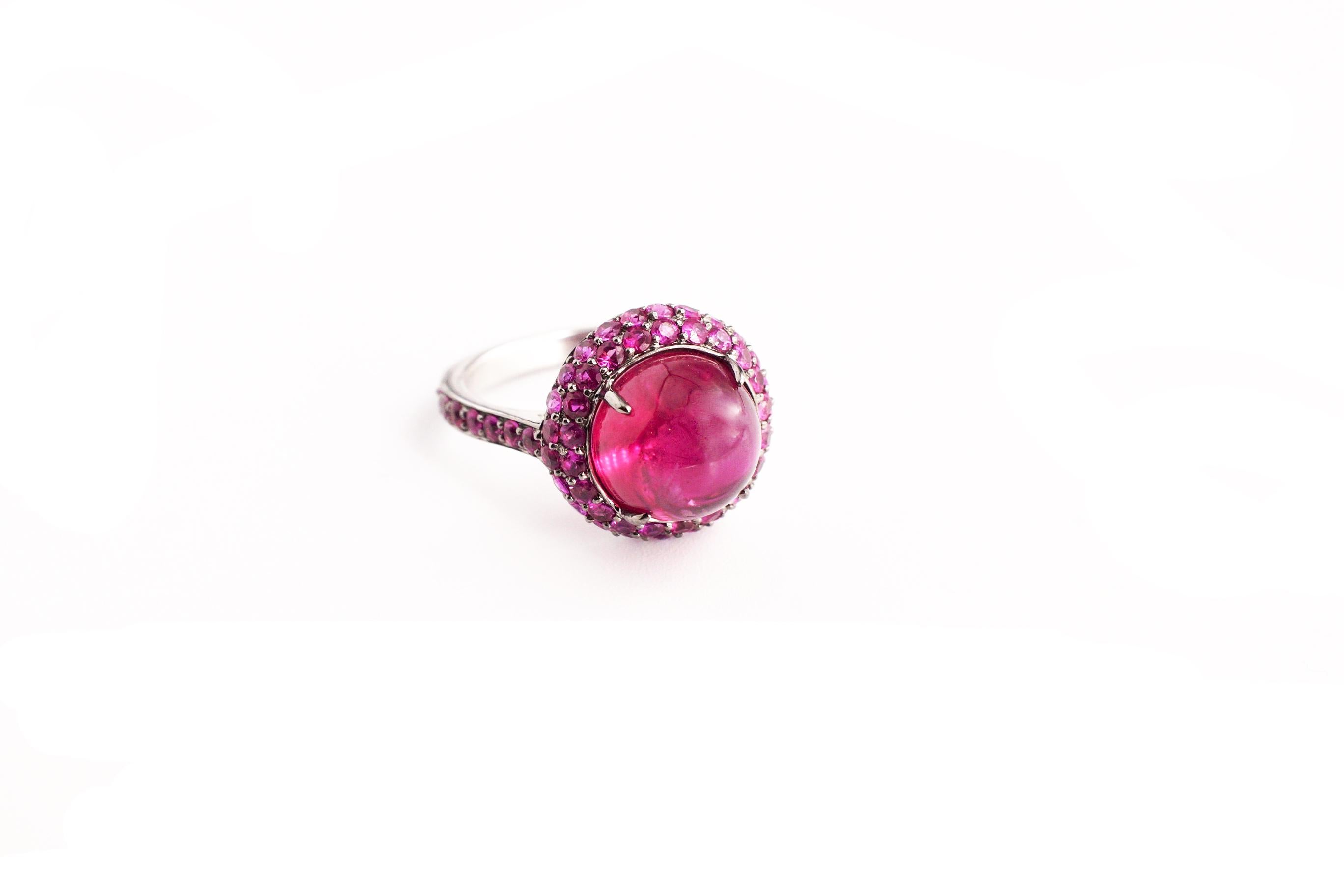 Jilly Ring – Rubellite
An eighteen-karat blackened white gold ring on a pink sapphire-encrusted shank, showcasing a high-domed rubellite cabochon that has been completely surrounded with pink sapphires.  
Size 6
Rubellite Total Weight – 5.20
