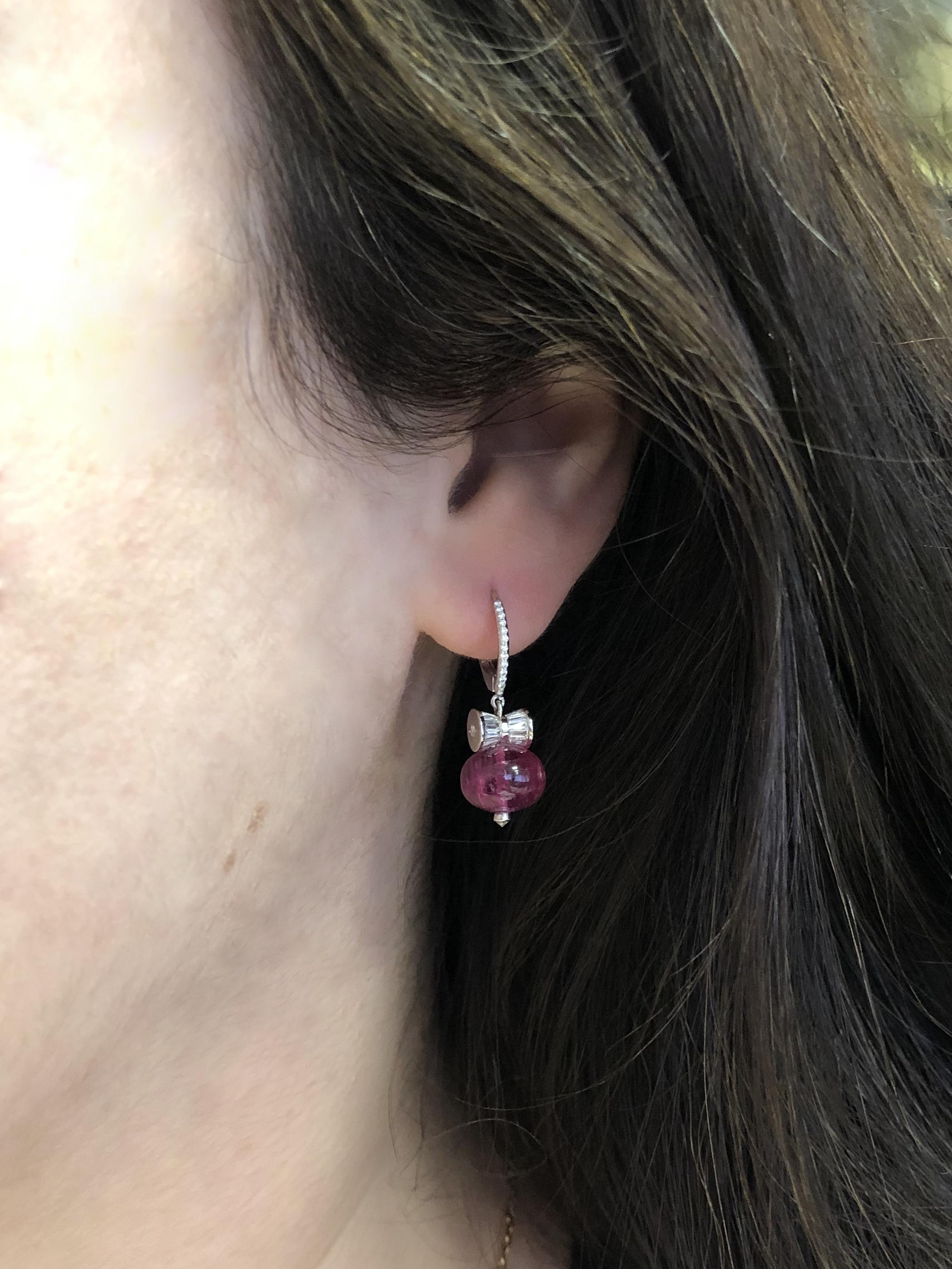 A pair of rubellite beads totaling approximately 13.47 carats are suspended from bowtie rondelles set with 51 tapered baguettes totaling approximately 0.66 carat and 30 round diamonds totaling approximately 0.14ct mounted in 18 karat white