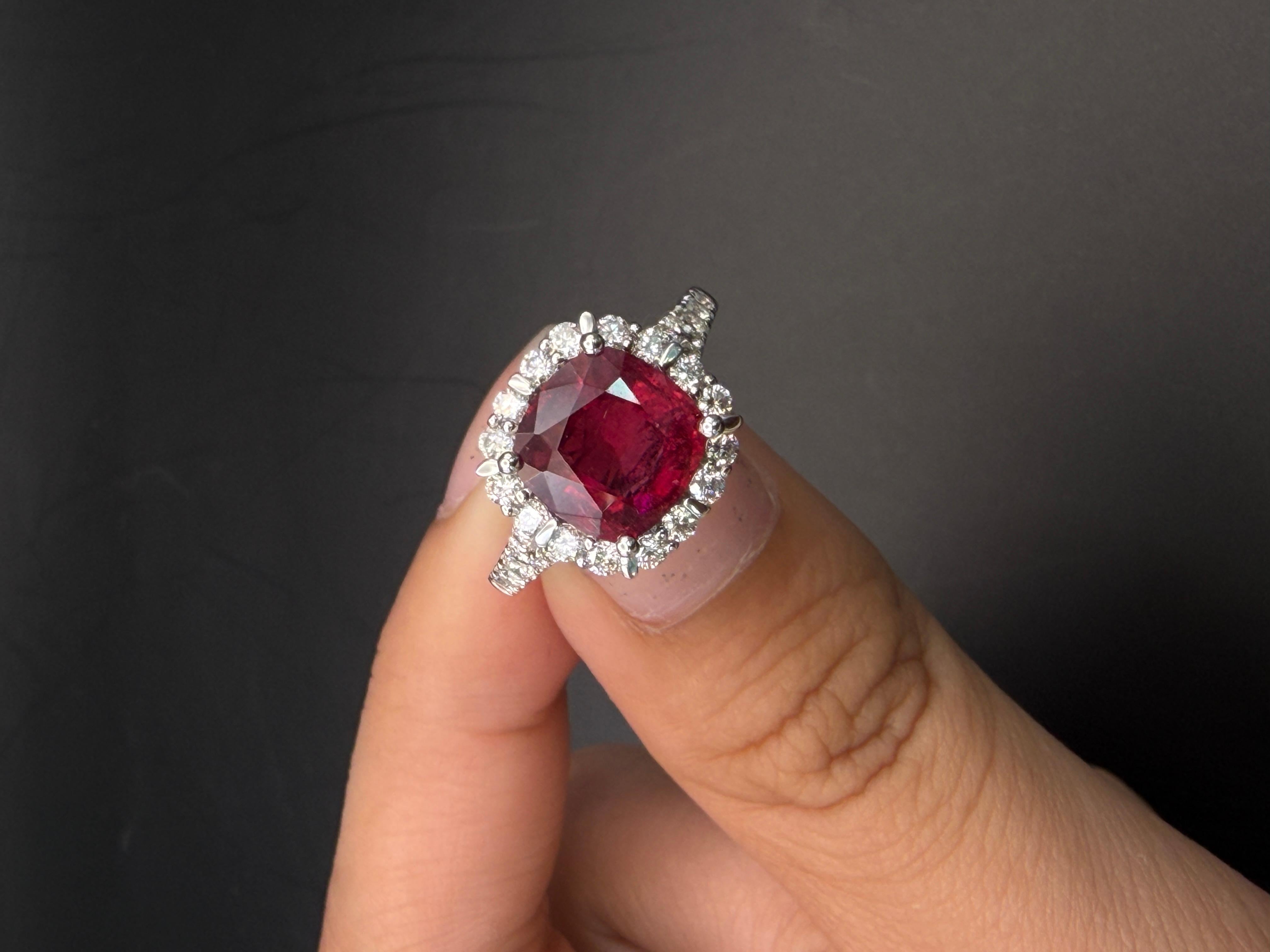 Este llamativo anillo de cóctel exhibe una vibrante rubelita de 2,69 quilates, apreciada por su intenso tono rojo frambuesa y su excepcional brillo. La piedra central de talla cojín está elegantemente enmarcada por un halo de diamantes brillantes
