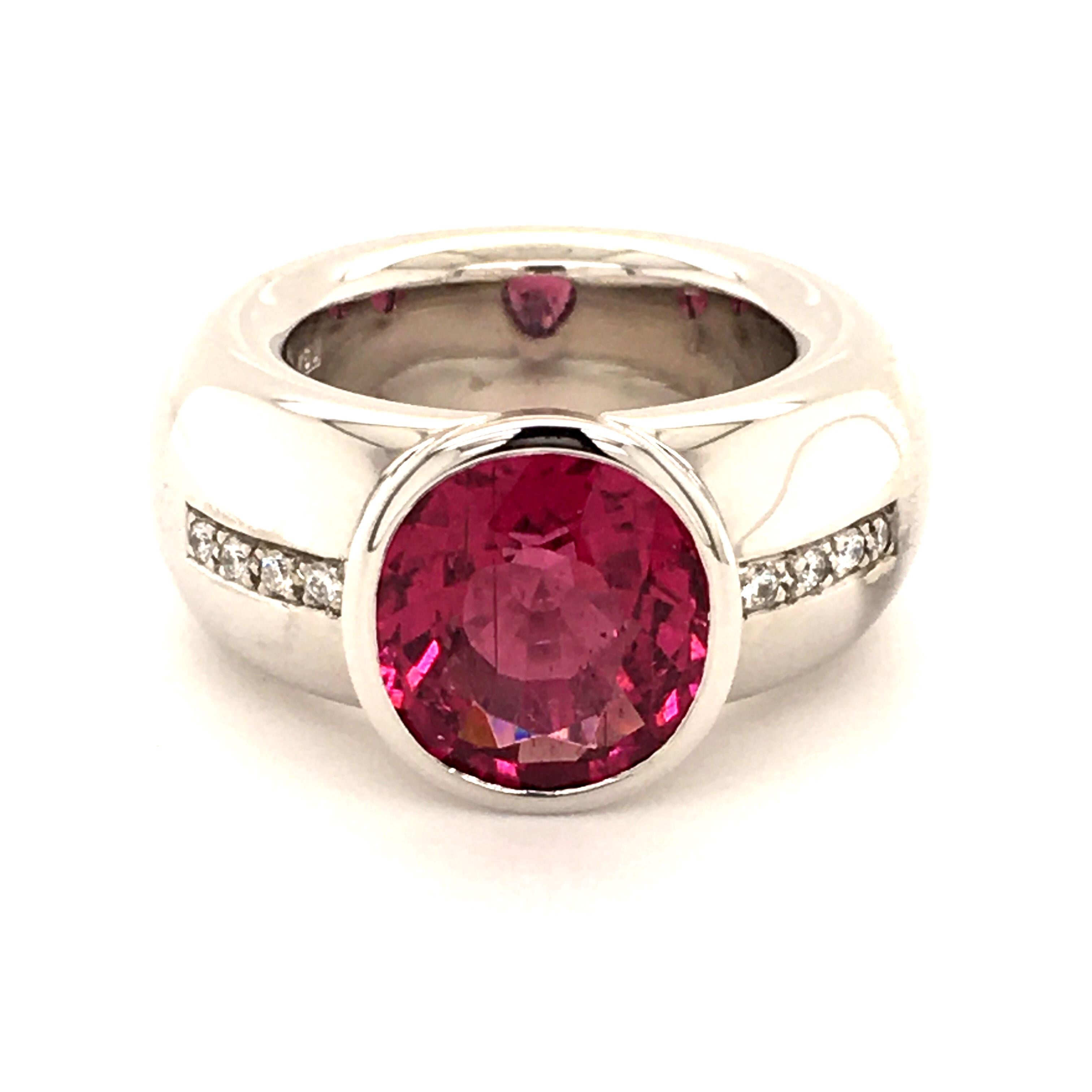 Massiv ring in white gold 750 bezel set with one stunning pink tourmaline (rubellite) of very intense color. The oval shaped gemstone weighs approximate 6.20 ct. RIng shank alongside set with 8 brilliant-cut diamonds totaling 0.12 ct of G/H-vs