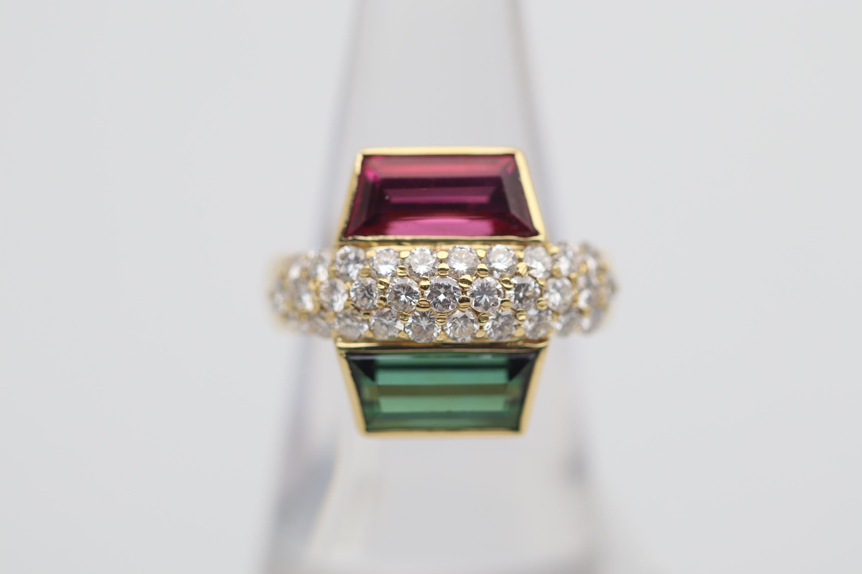 A stylish and chic ring features two gem tourmalines, one a vibrant red rubellite while the other a deep intense green. They weigh 1.75 and 1.51 carats respectively, and are matching in size, shape, and color intensity. Between the two tourmalines