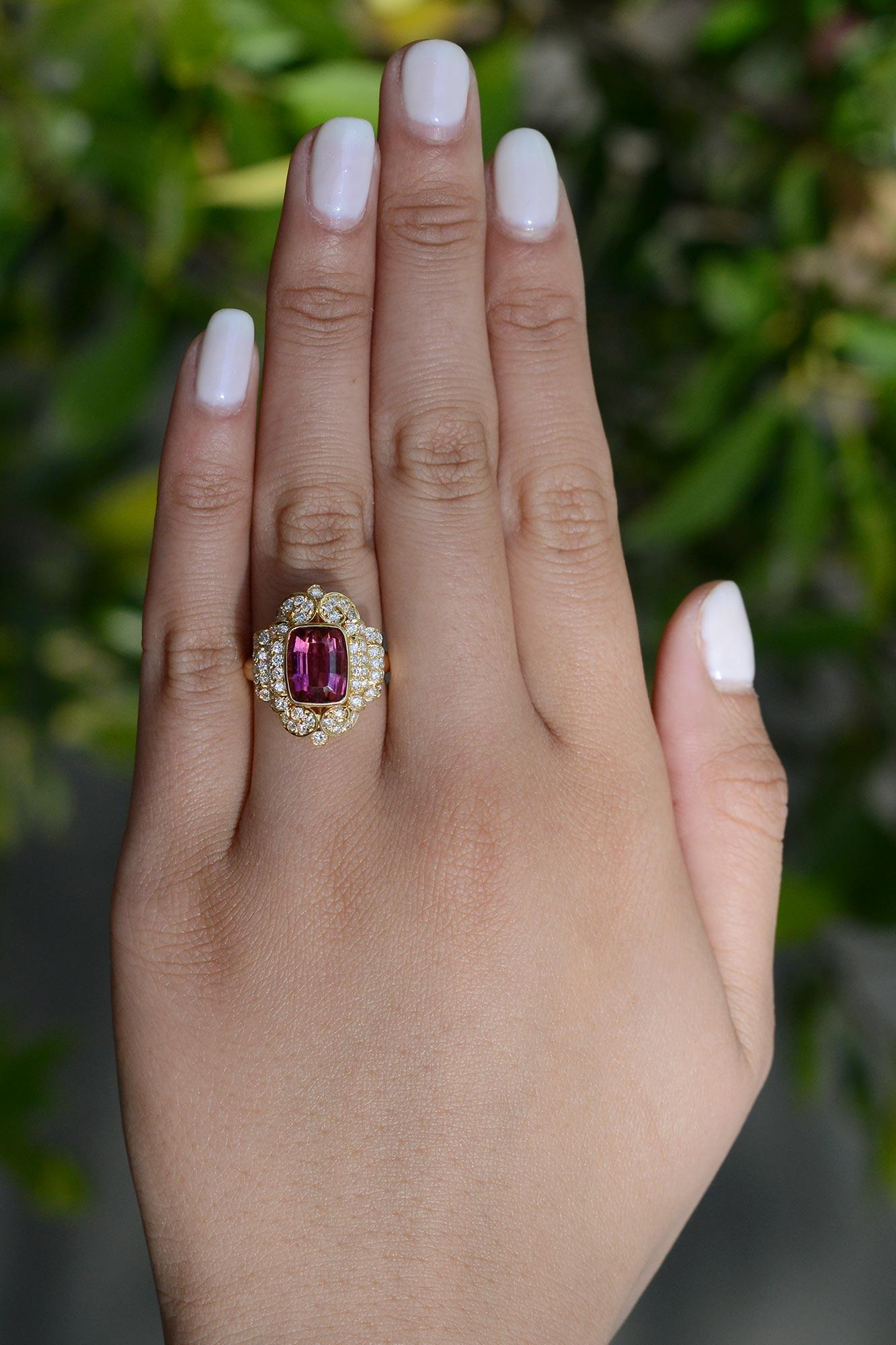 The blend of the rich 18k yellow gold, glimmering diamonds, and enthralling pink tourmaline make for a ravishing ring. The rubellite tourmaline has extraordinary color, a bright pink with gleams of orange showcased in a bezel setting. The diamonds