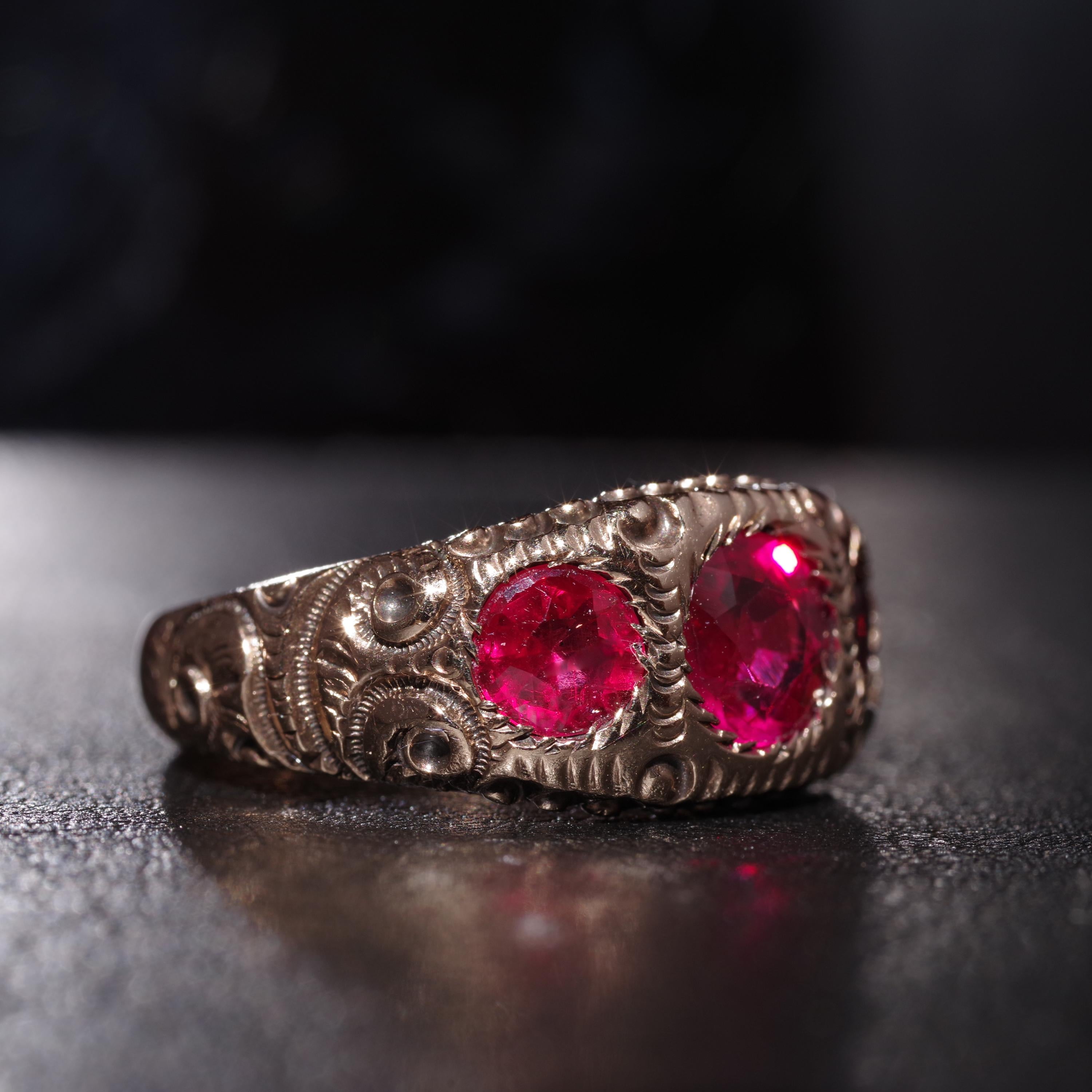 Dating to approximately 1890, this American-made men's ring features three gemmy, bright and vivid rubellite tourmaline stones set within a deeply carved 10K yellow gold band. Two round faceted rubellite gems weighing approximately half-a-carat each
